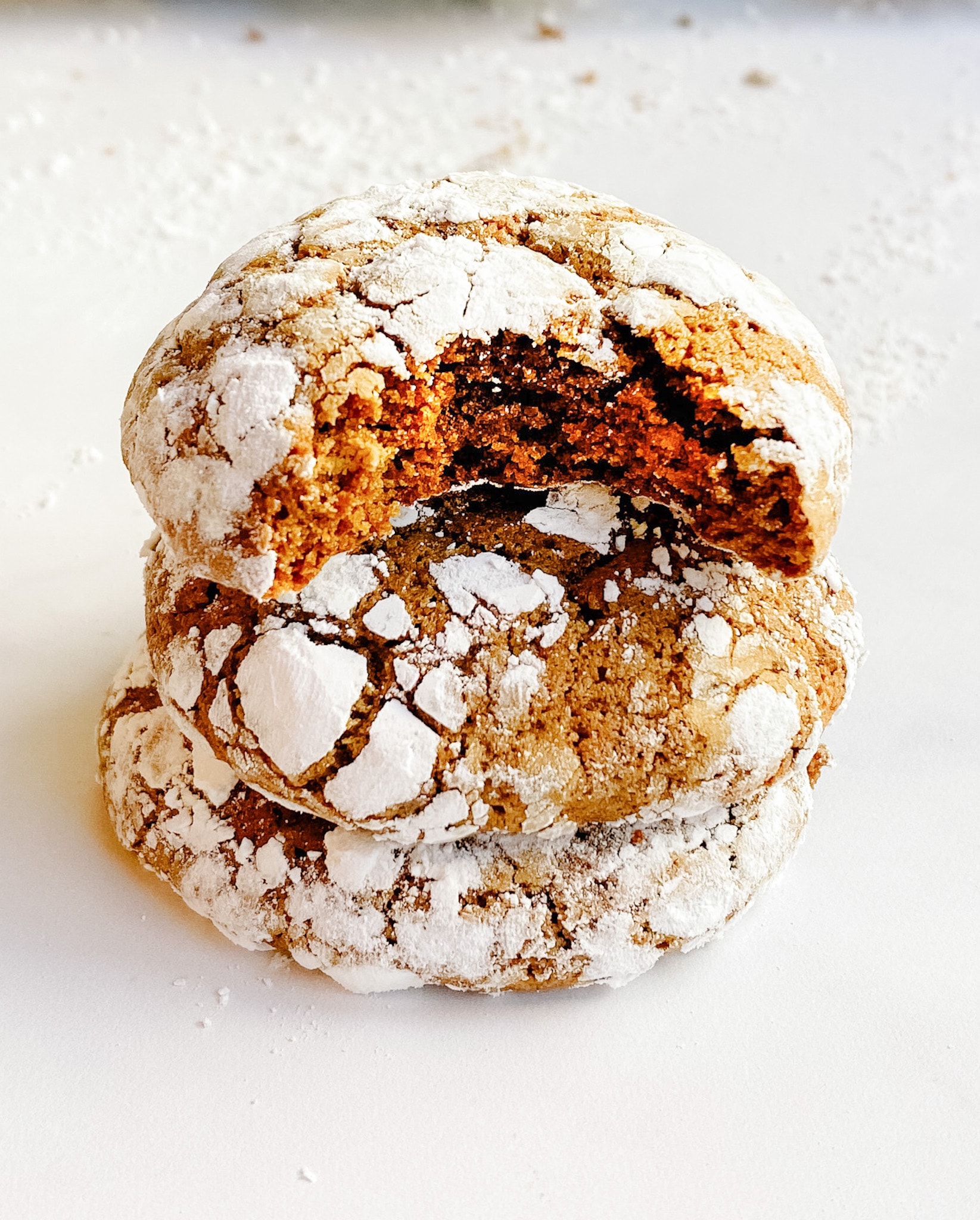 Gingerbread crinkle cookies. A stack of three with the top cookie having a bite out of it