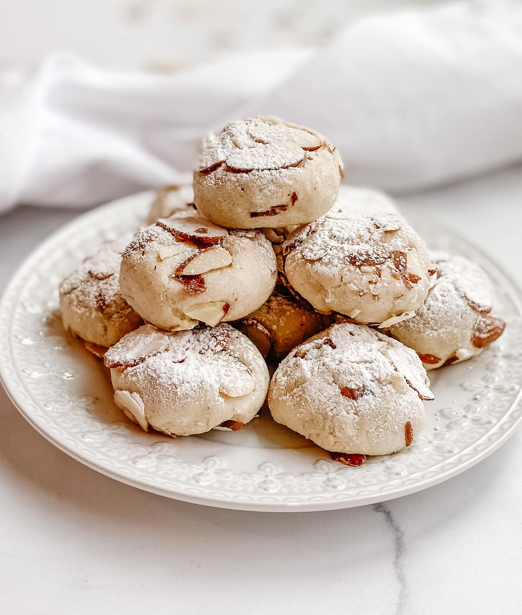 A front view of the stack of amaretti cookies. The cookies are topped with powdered sugar and almonds.