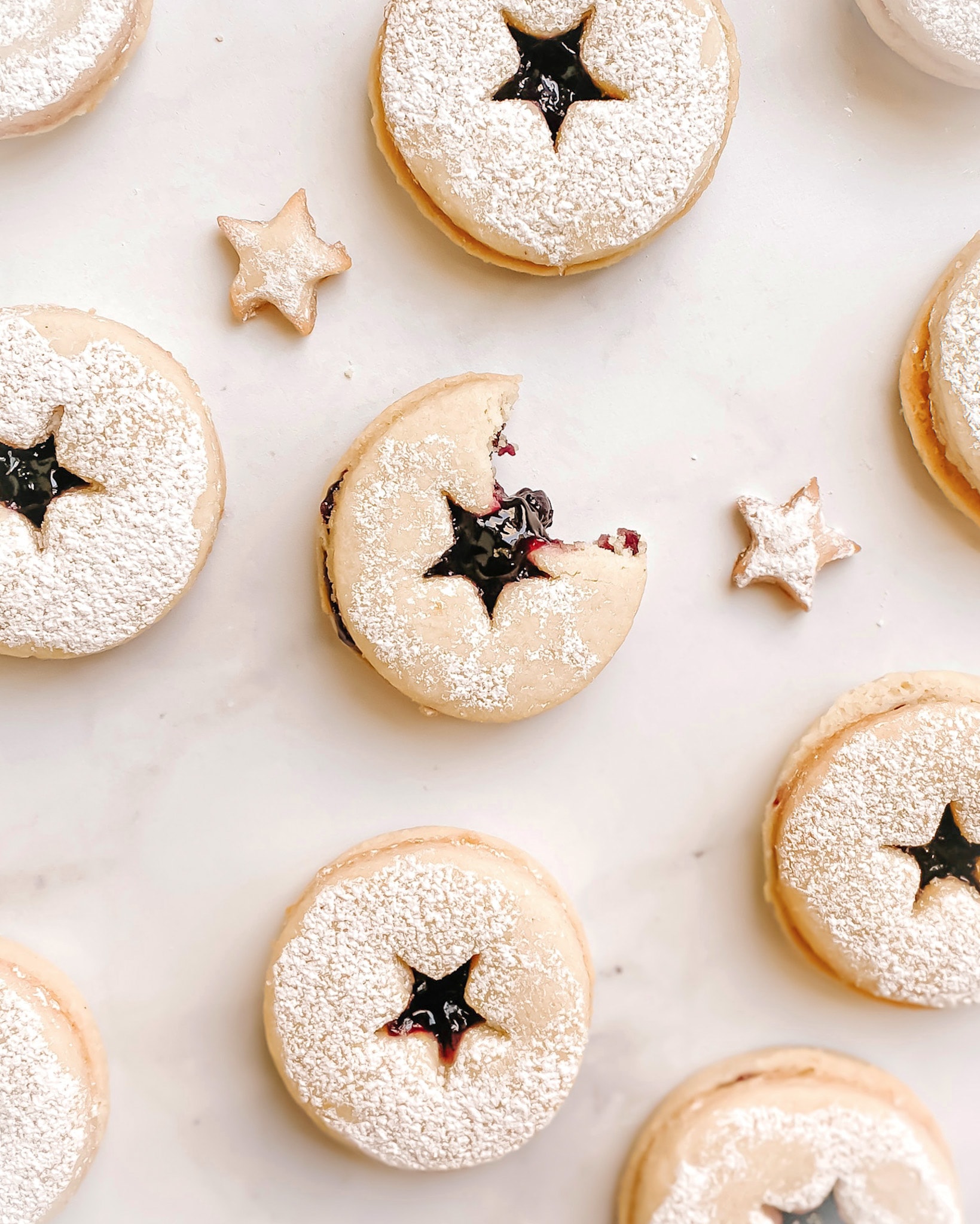 gluten-free linzer cookies with stars cut into the middle of the cookies, blueberry jam can be see through the star cutout