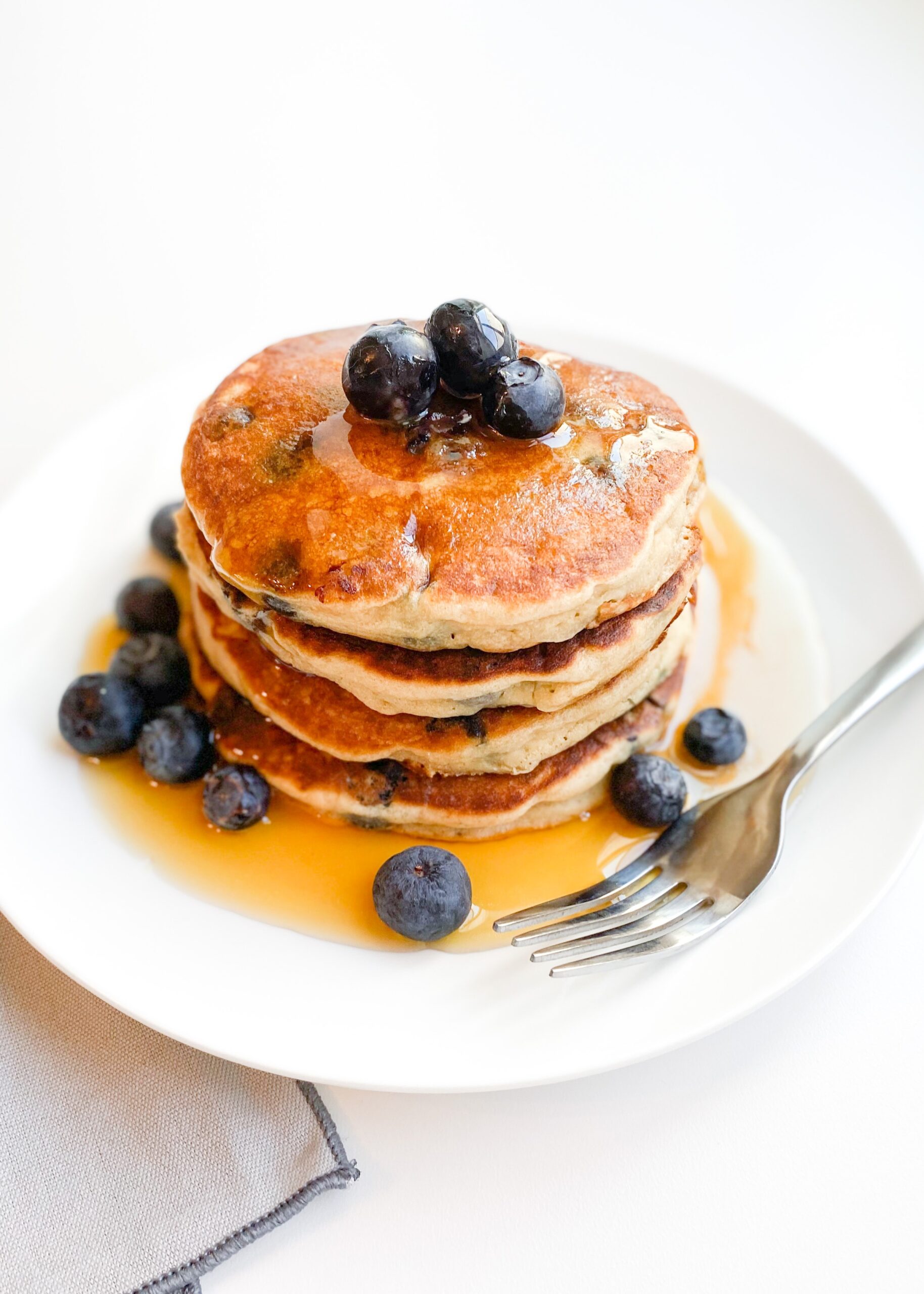 four gluten-free blueberry pankes with maple syrup.