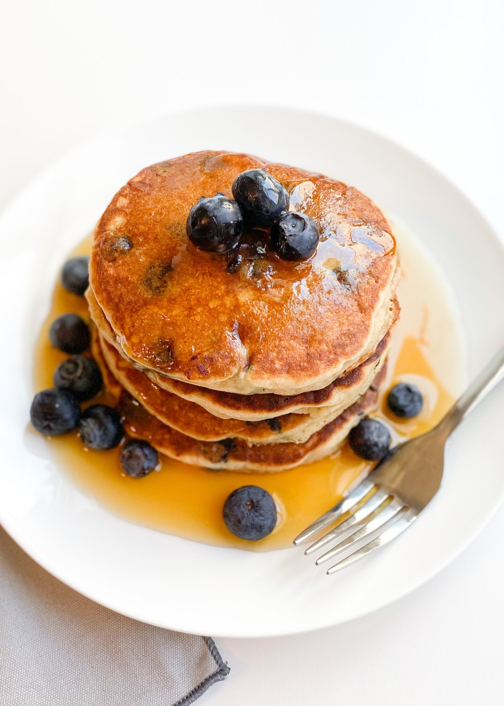stack of gluten-free pancakes in syrup and blueberries.