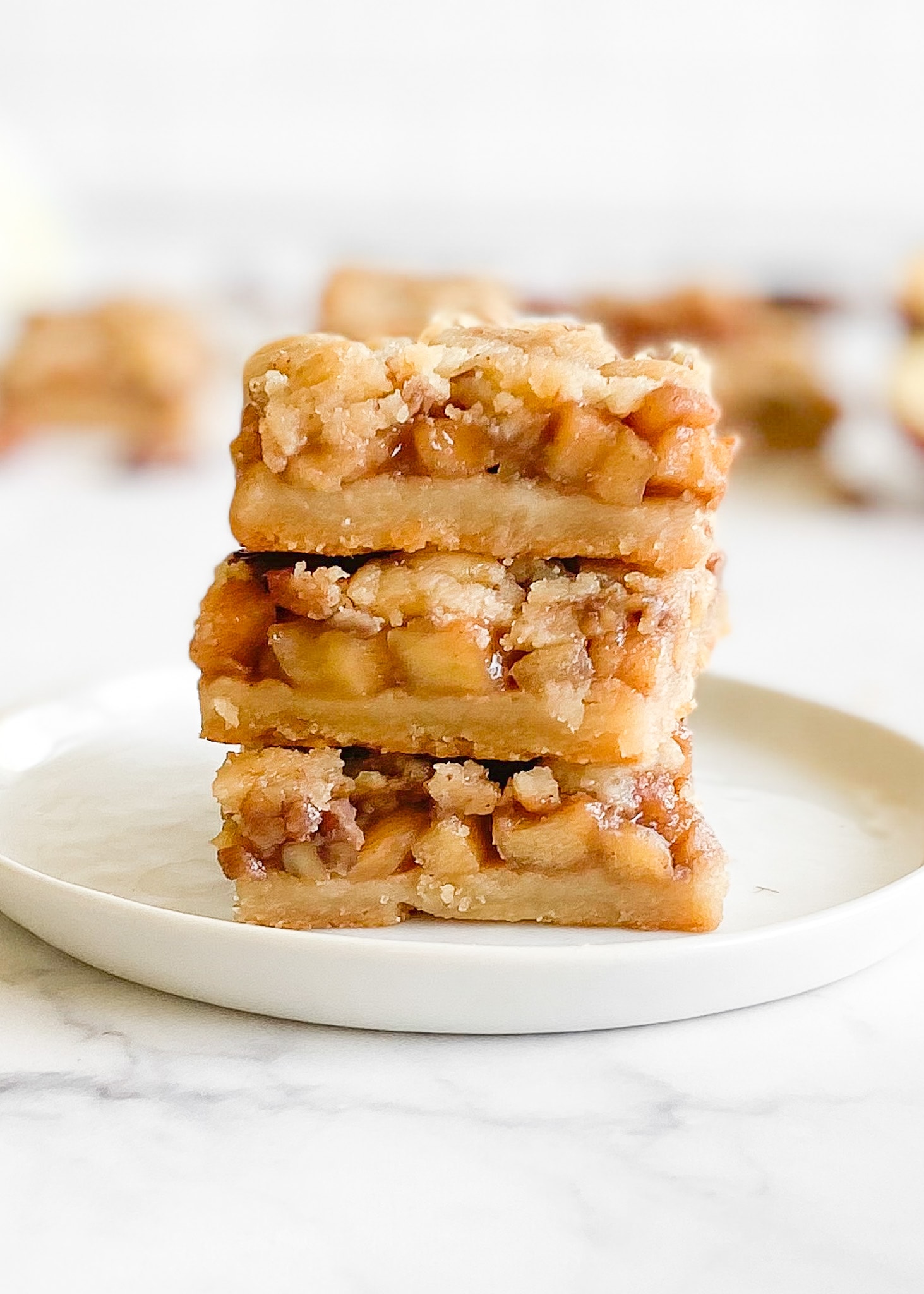 Three apple crumble bars stacked on top of each other. Large chunks of apples are layered in the bar.