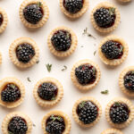 this is a photo of all the blackberry tartlets with brie spread across a light colored backdrop.