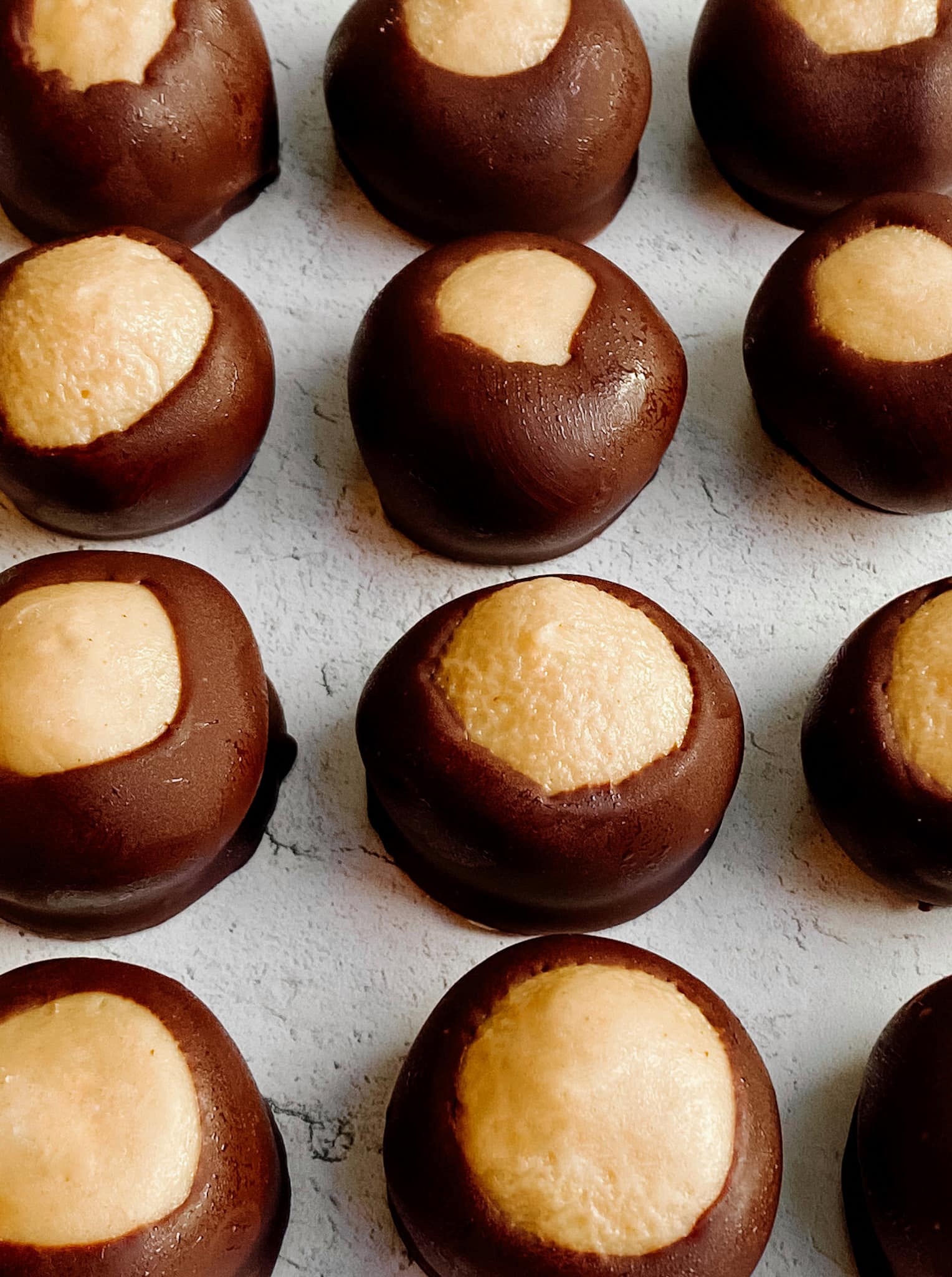 A close up spread of peanut butter buckeyes, a peanut butter center surrounded by chocolate.