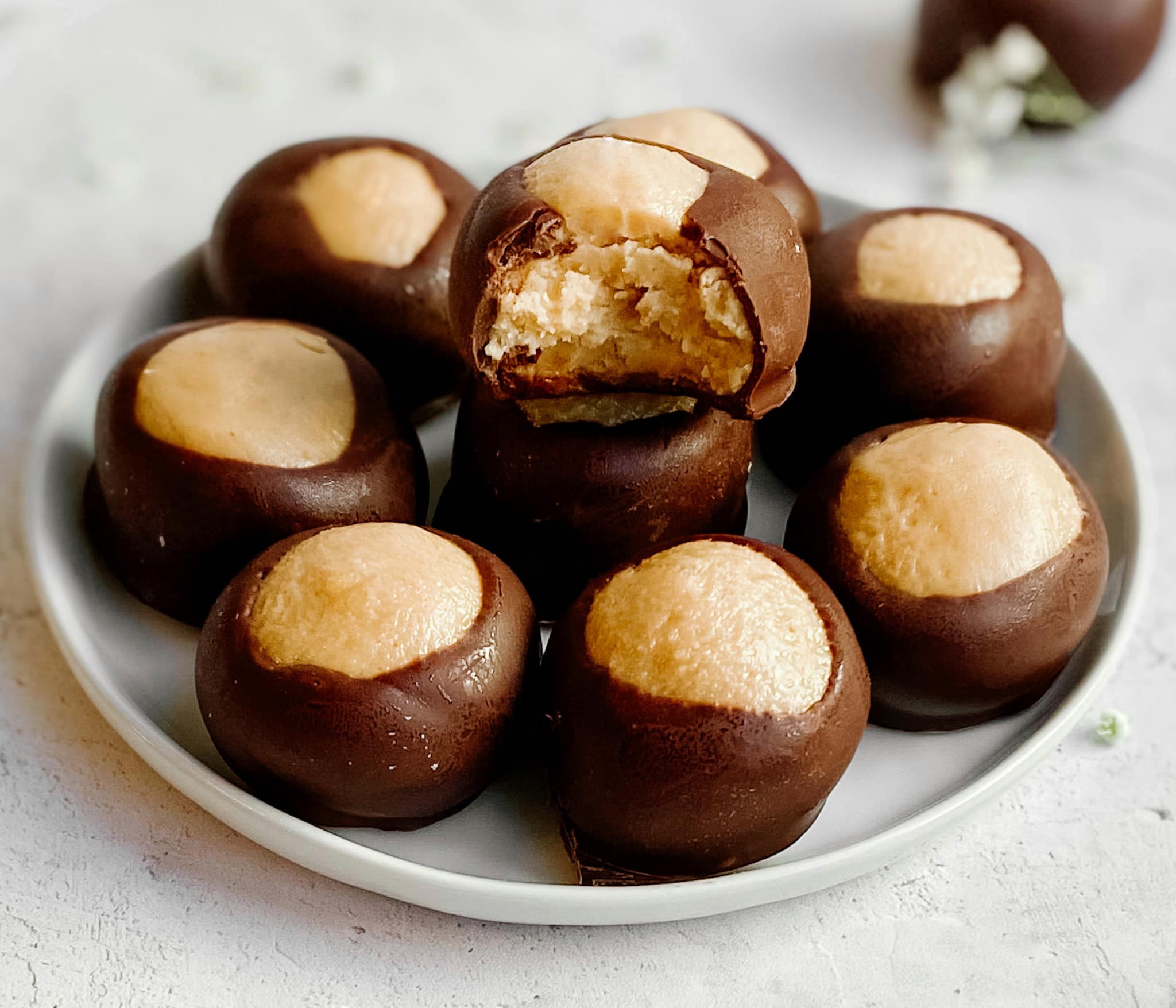 A stack of buckeyes on a plate. A single buckeye on the top of the pile has a bite taken out of it.