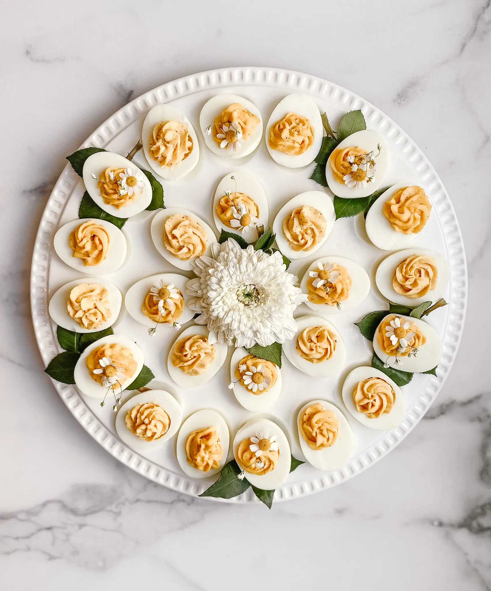 An aerial photo of my deviled eggs on a decorative lazy susan. A decorative  flower is in the middle of the platter.