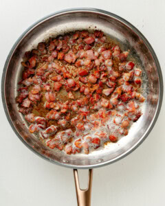 Sauteéing bacon in a large skillet.