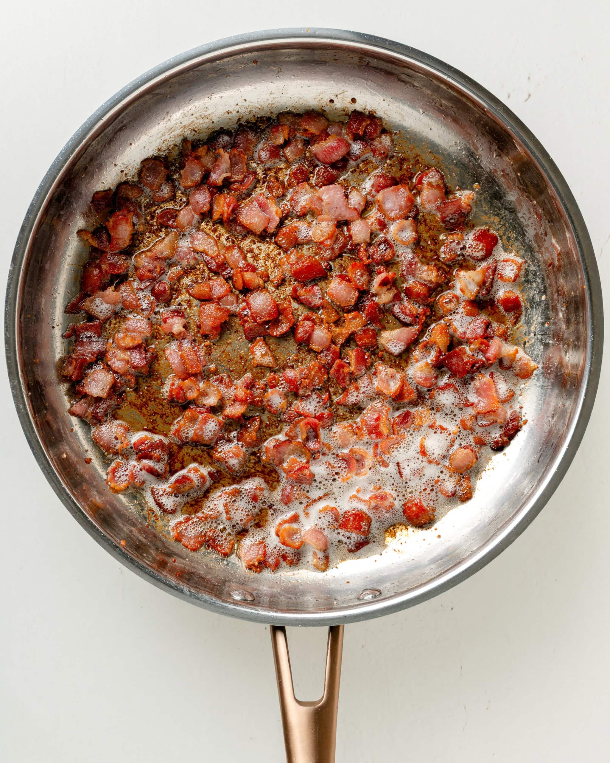 Sauteéing bacon in a large skillet.