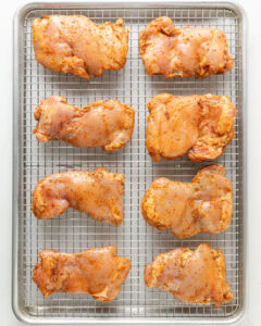 Chicken thighs on a baking rack.