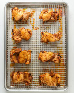 Fully baked crispy boneless chicken thighs on a baking rack, right out of the oven.