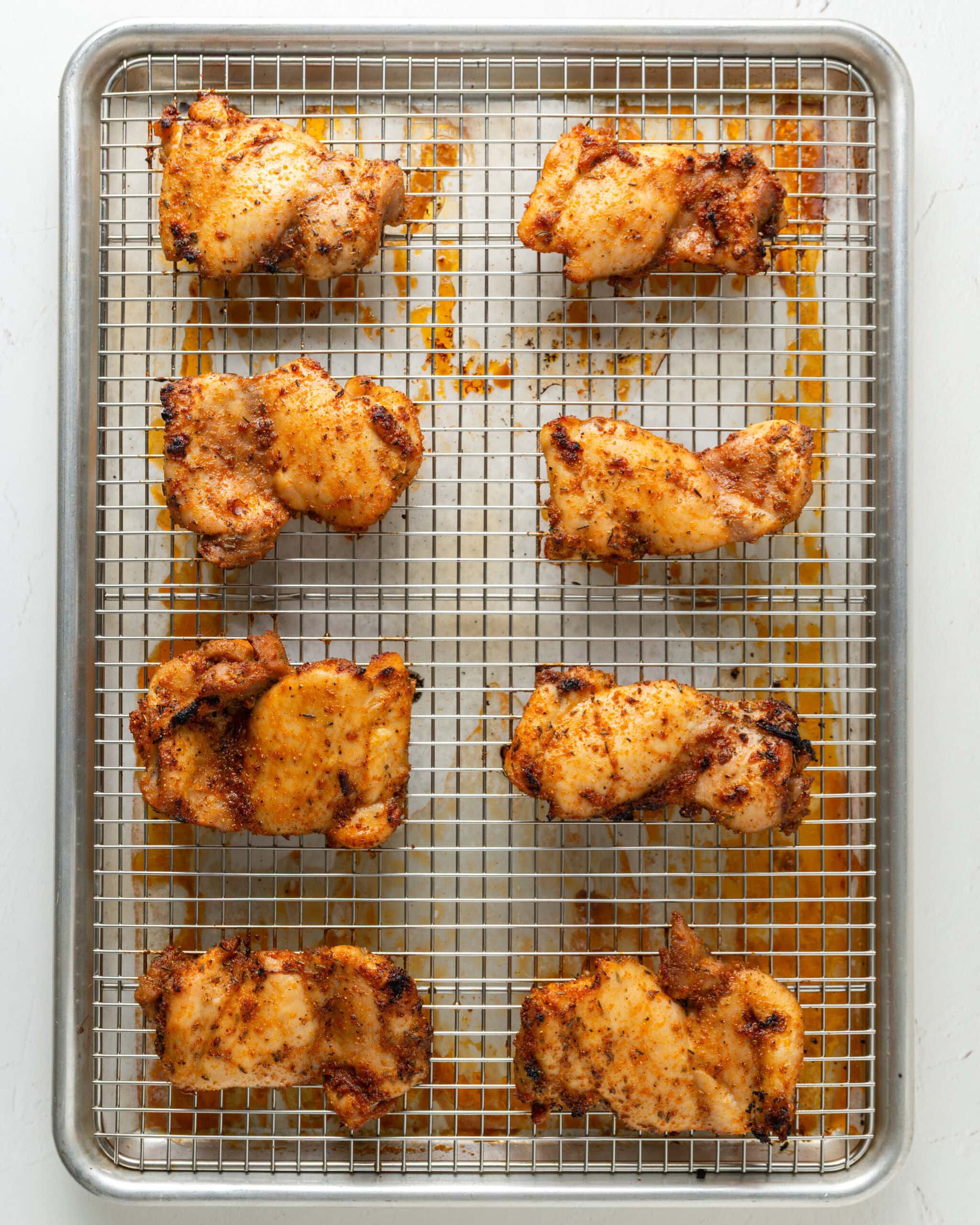 Fully baked boneless skinless chicken thighs on top of a baking rack.