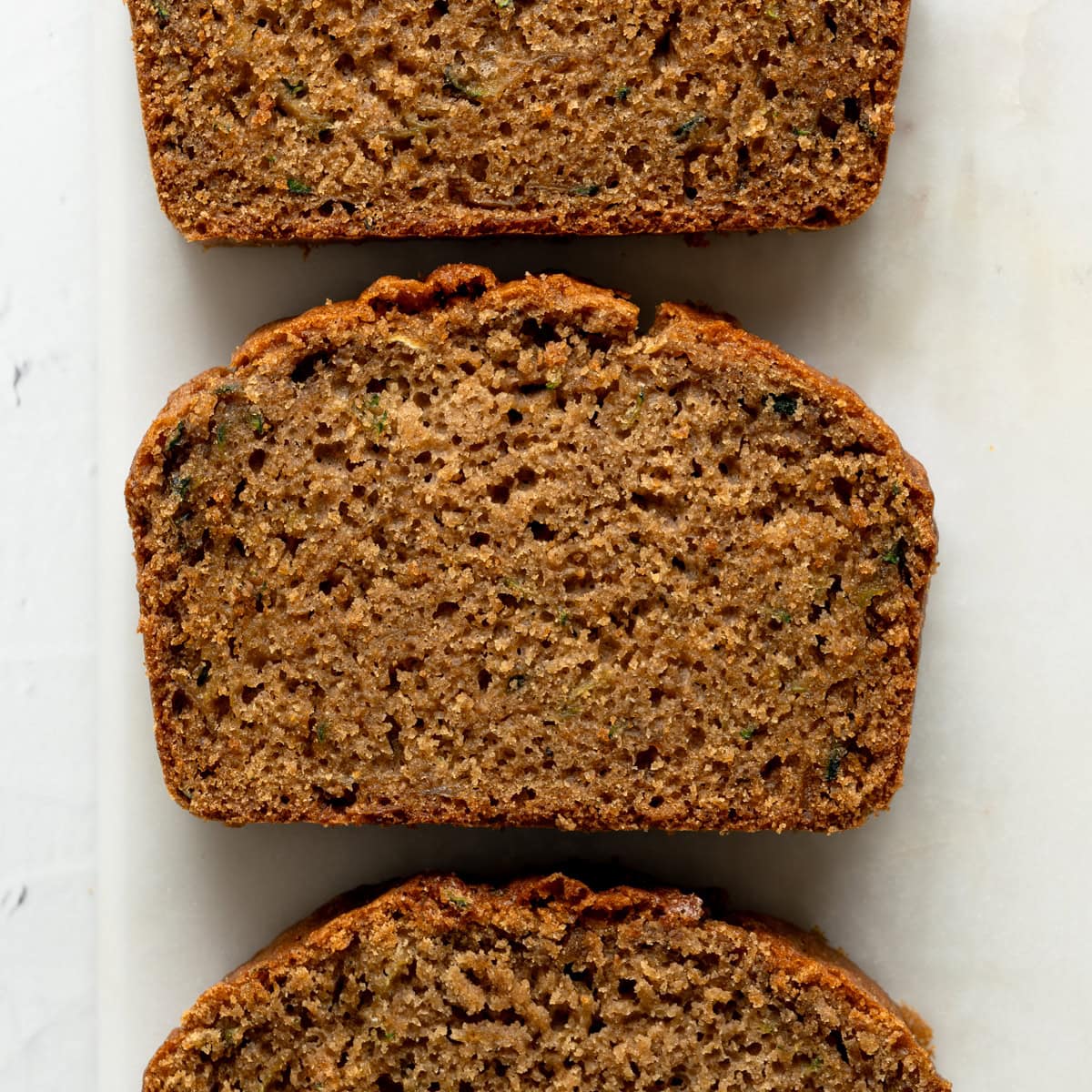 Close-up shot of three slices of gluten-free zucchini bread highlighting its moist, soft crumb.