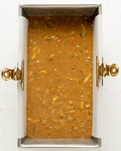 Gluten free zucchini bread batter poured into a 9x5 inch loaf pan lined with parchment paper.