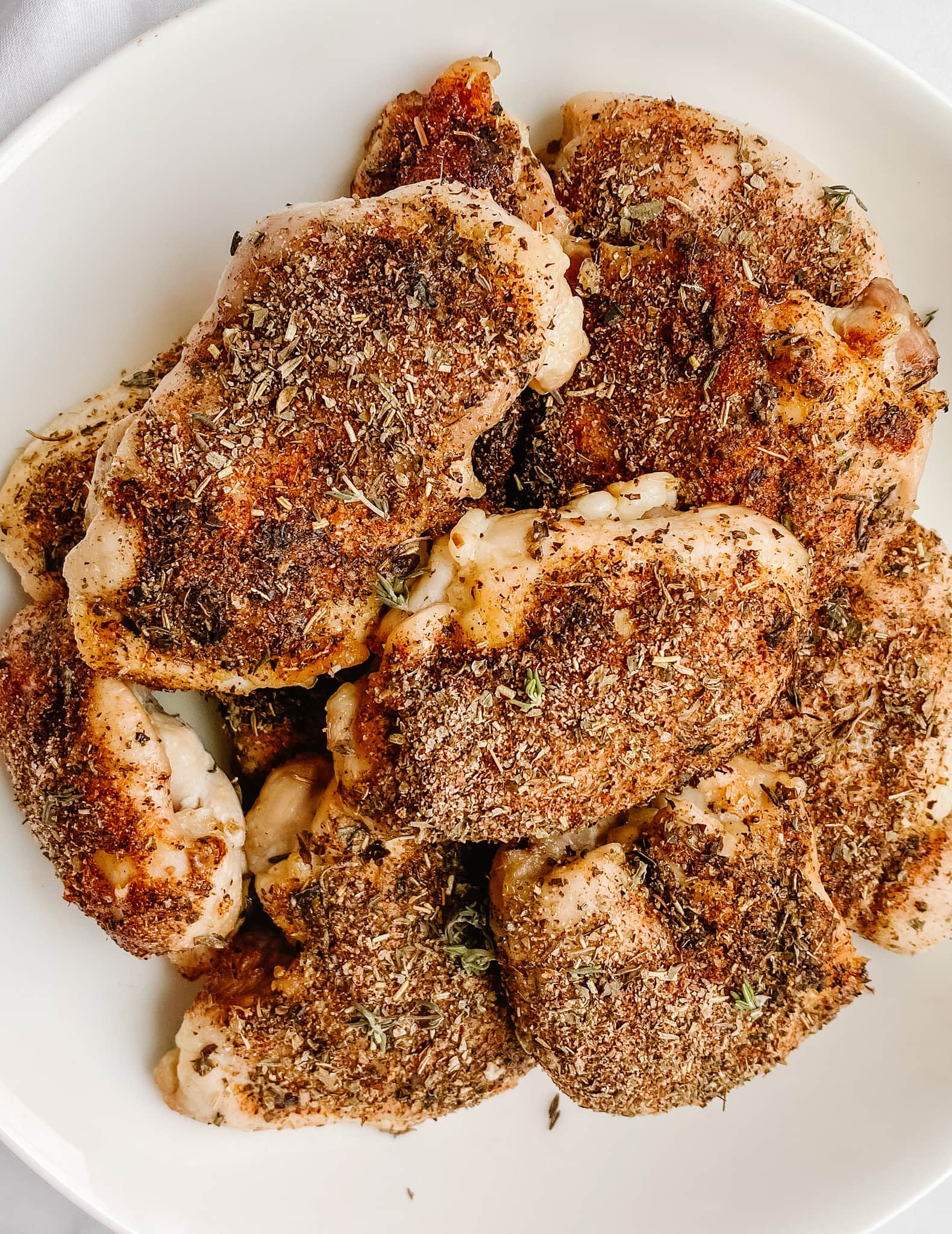 aerial shot of gluten free baked chicken with Italian spices on a white plate