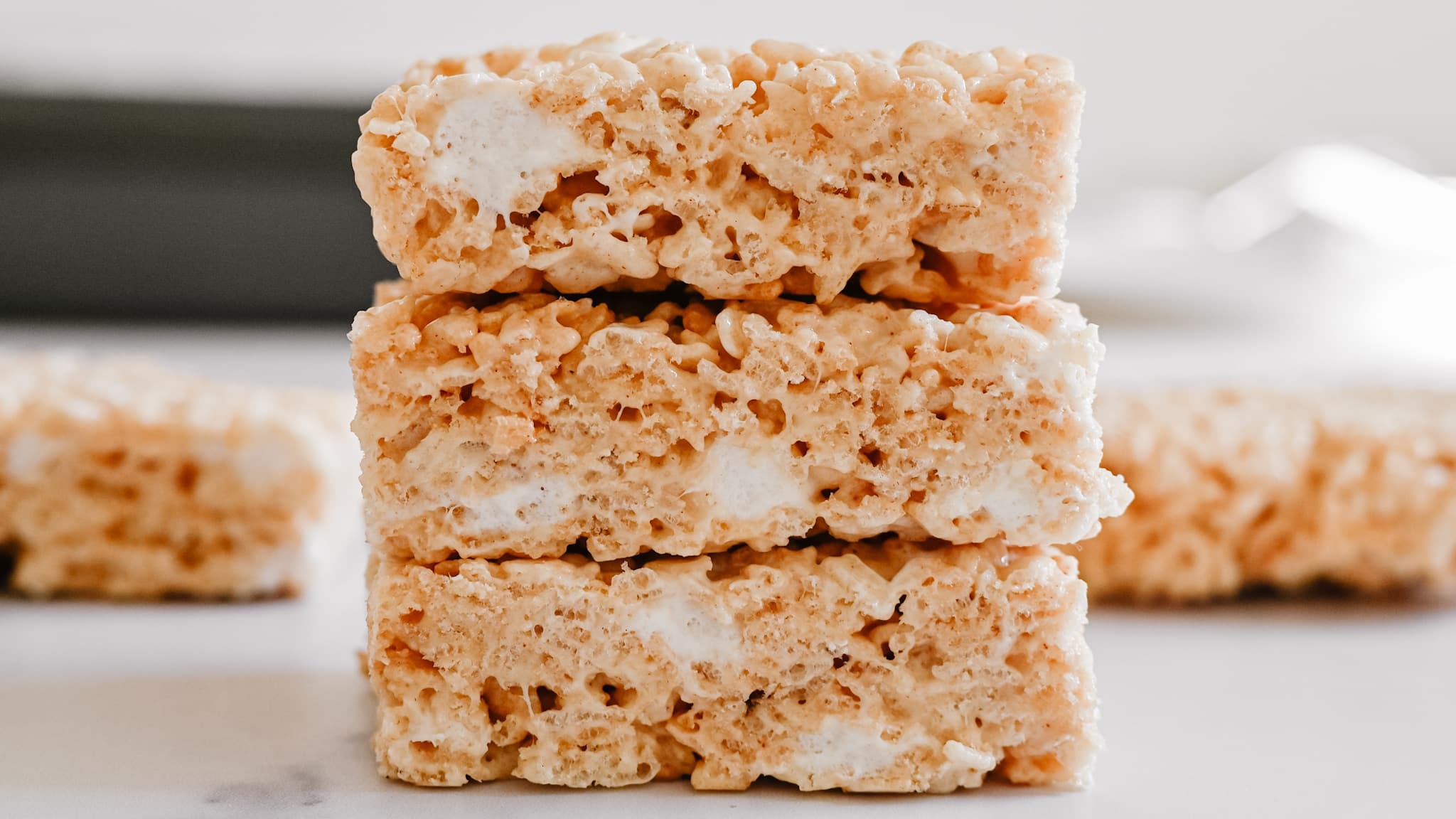 An image of three stacked rice krispies treats from the side view showing the marshmallows in the center.