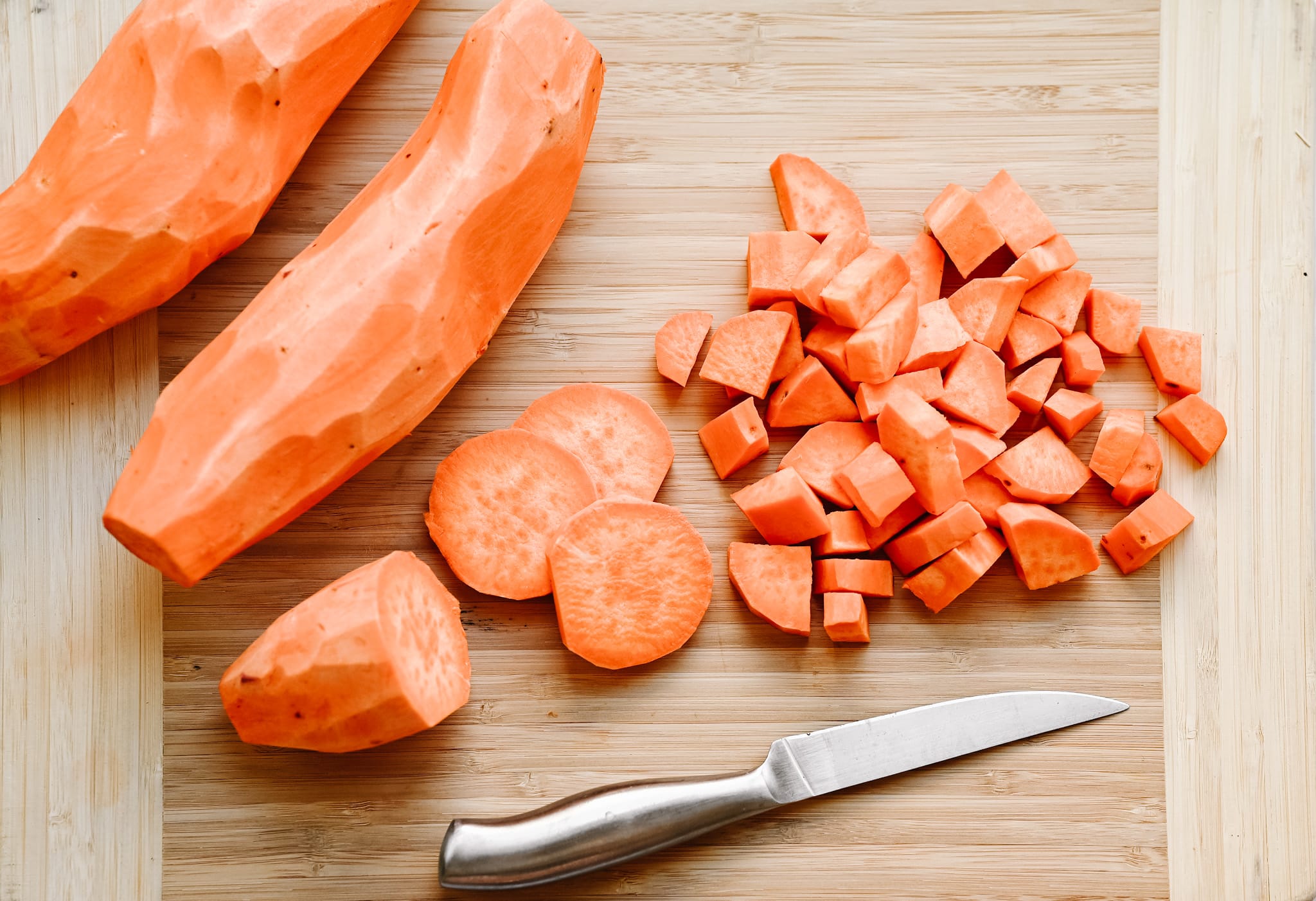 An image of diced and skinned sweet potatoes on a chopping board.