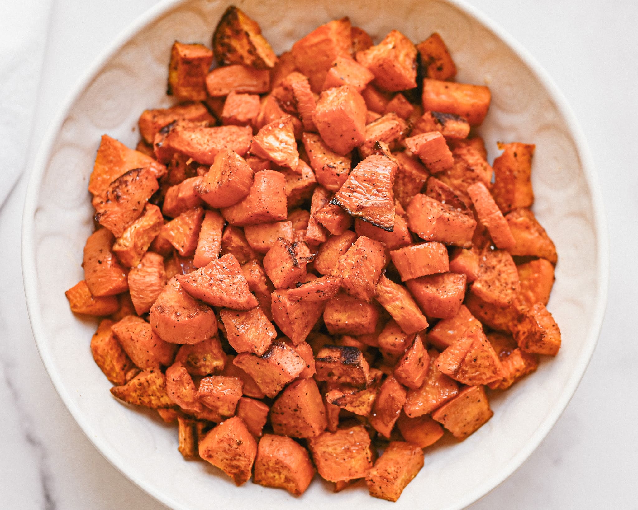 A cropped image of orange sweet potatoes in a white bowl.