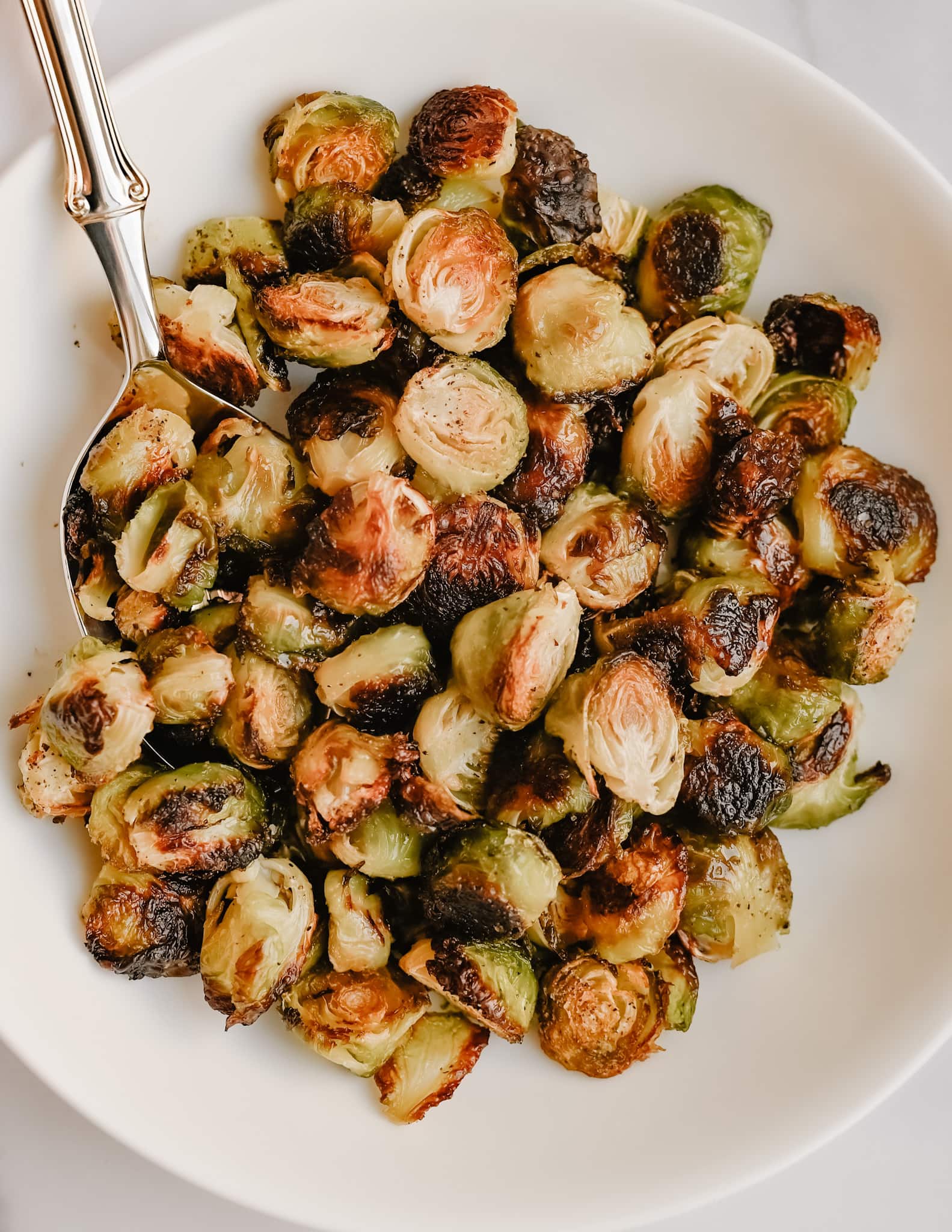 Crispy roasted brussels sprouts in a white bowl. 