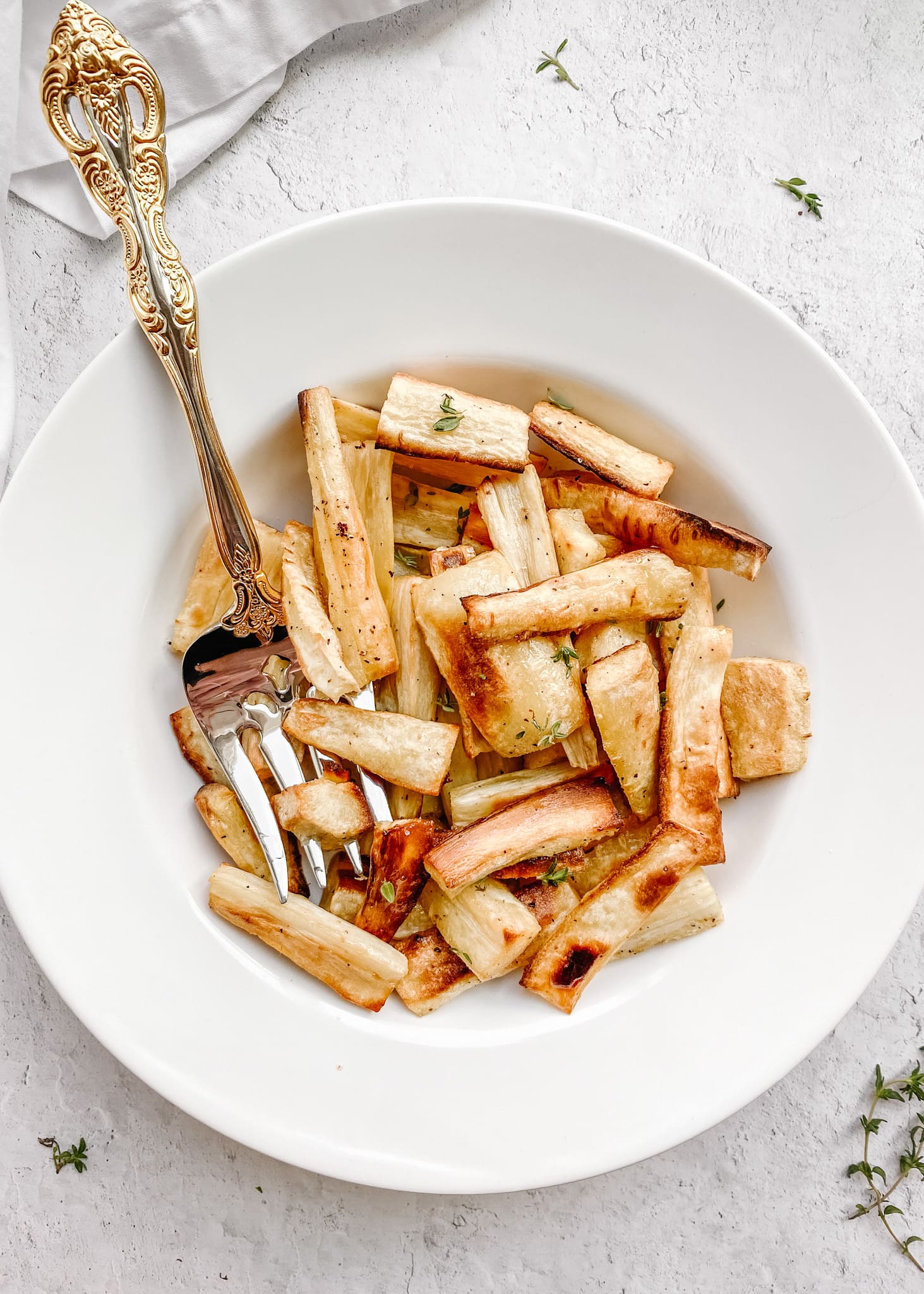 gold serving fork in a bowl of roasted parsnips
