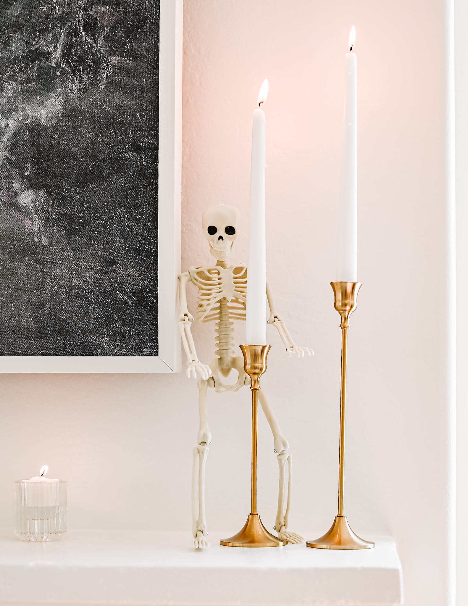 white candles with a skeleton standing next to them