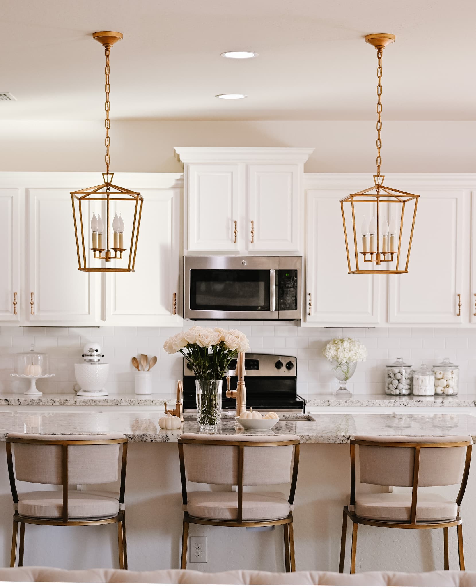 a kitchen with hanging gold lantern lights, 3 stools and halloween decorations