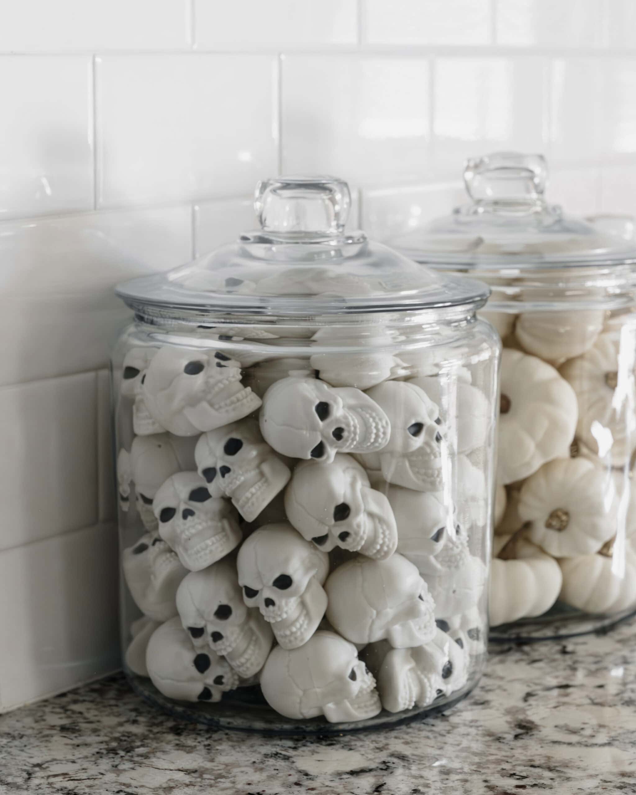 shot of a glass jar with plastic skeleton heads and white marshmallow ghosts in another jar