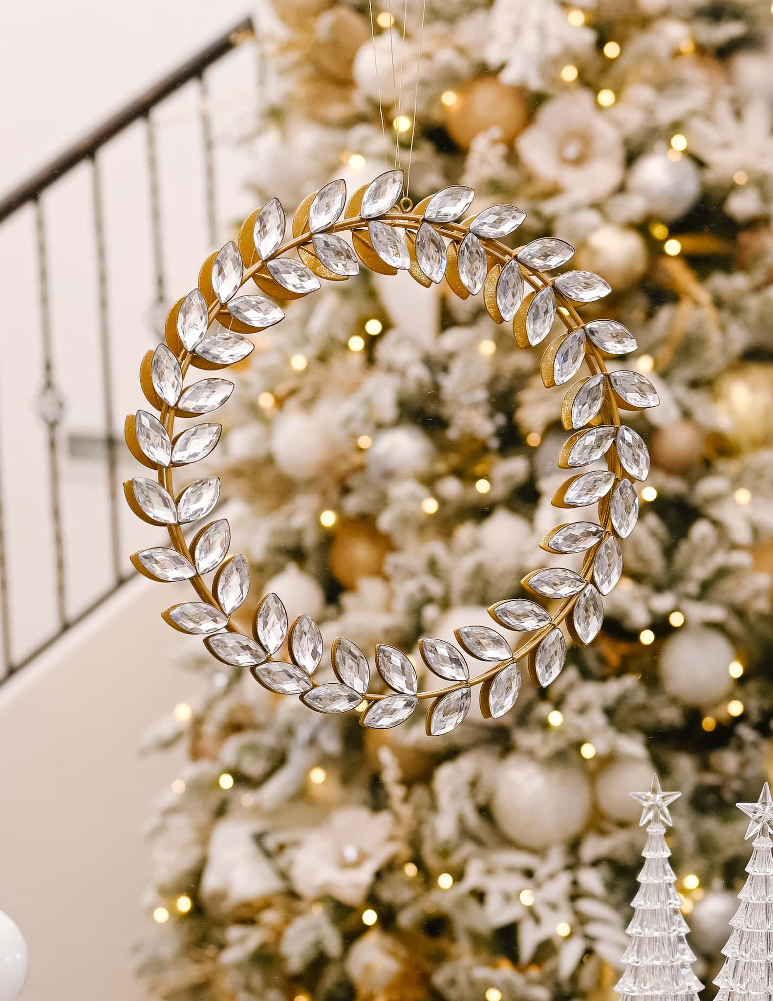 a gold wreath with crystal decoration hangs from a gold mirror