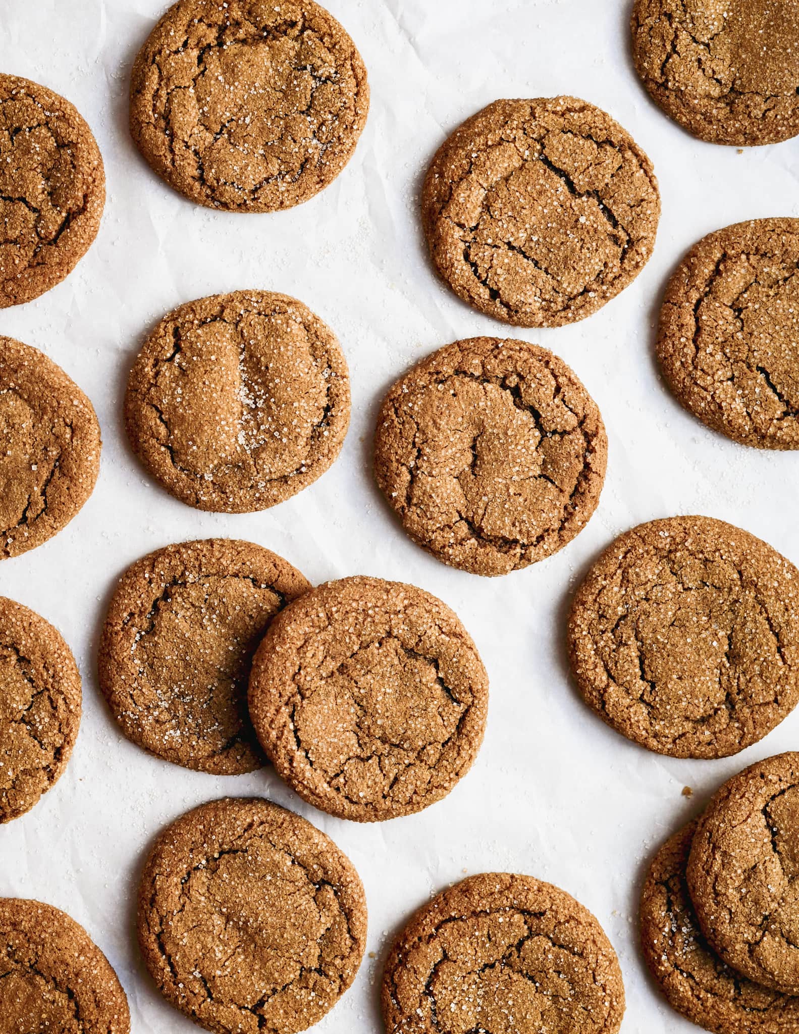 a lot of gluten free soft molasses cookies with soft cracks and a crunchy sugar topping can be seen