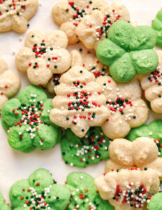 pile of gluten free spritz cookies. White and green cookies with circular sprinkles.