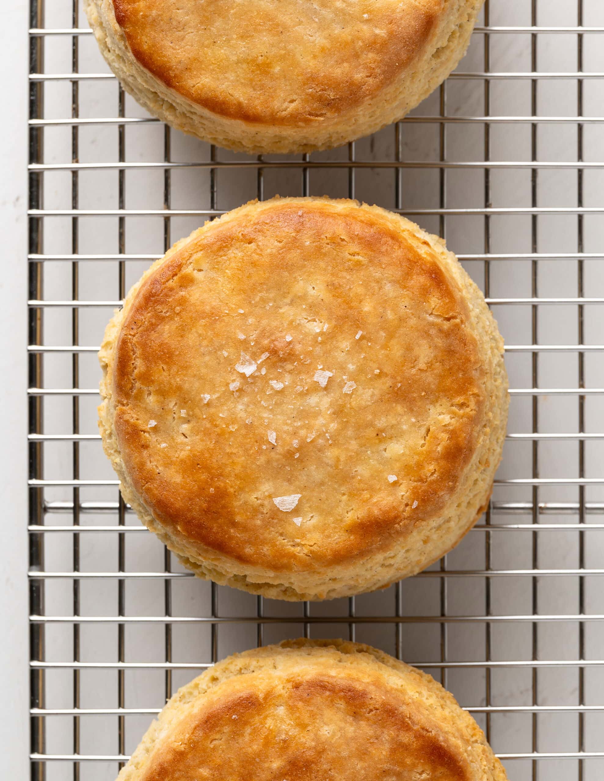 Close up shot of flaky golden brown buttermilk biscuits with flaky sea salt.