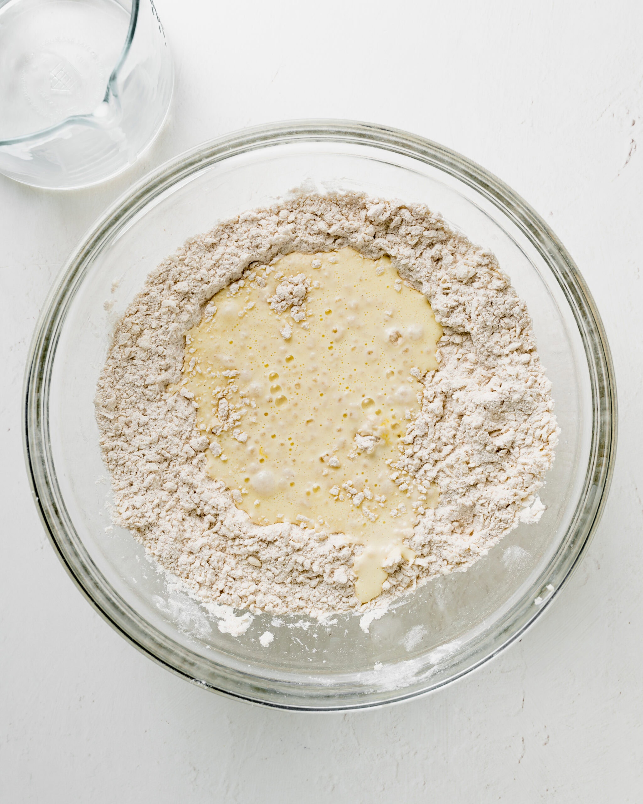 Adding the wet ingredient to the dry ingredients for buttermilk biscuits.