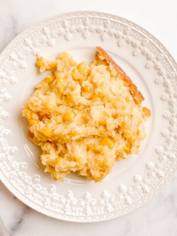 An image of a gluten-free corn casserole serving on a white decorative ceramic plate.