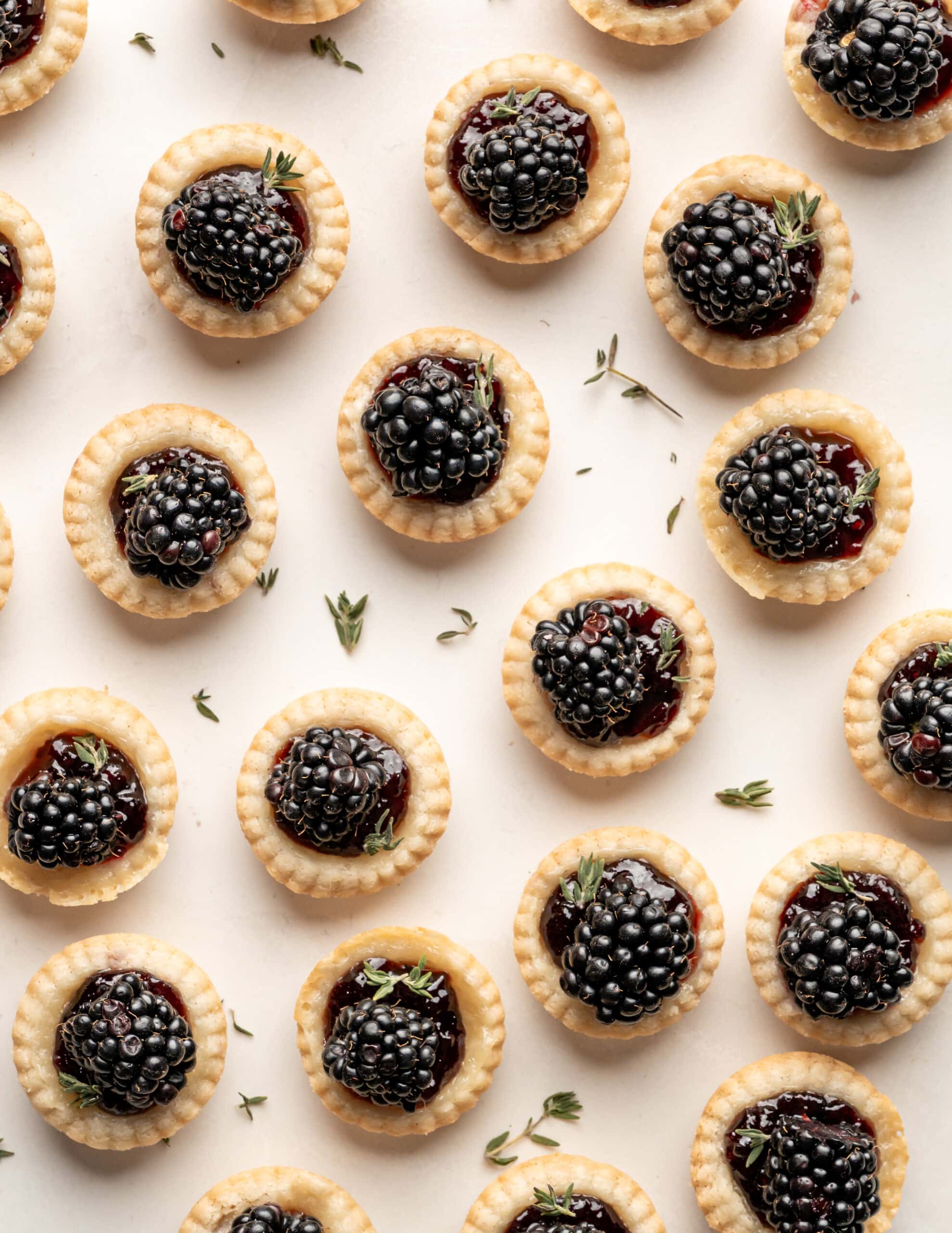 Miniature tart shells filled with melted brie, blackberry jam, and topped with fresh blackberries and thyme.  