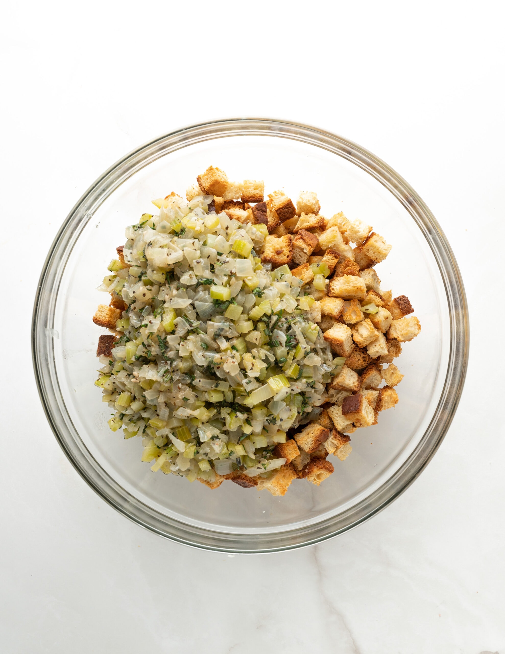 A large clear both with toasted gluten-free bread cubes, and onion/celery mixture. 