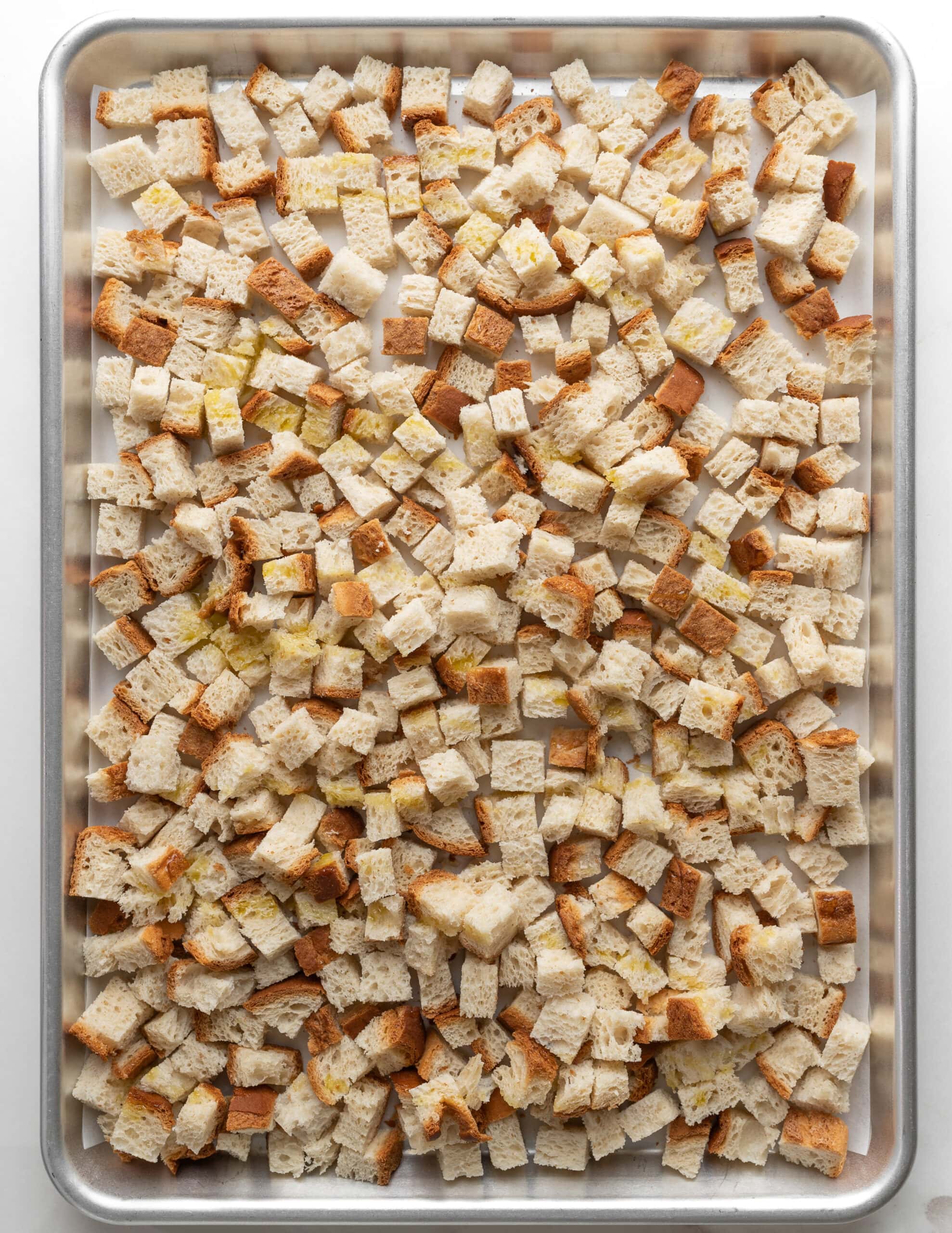Large silver baking tray with diced bread cubes.