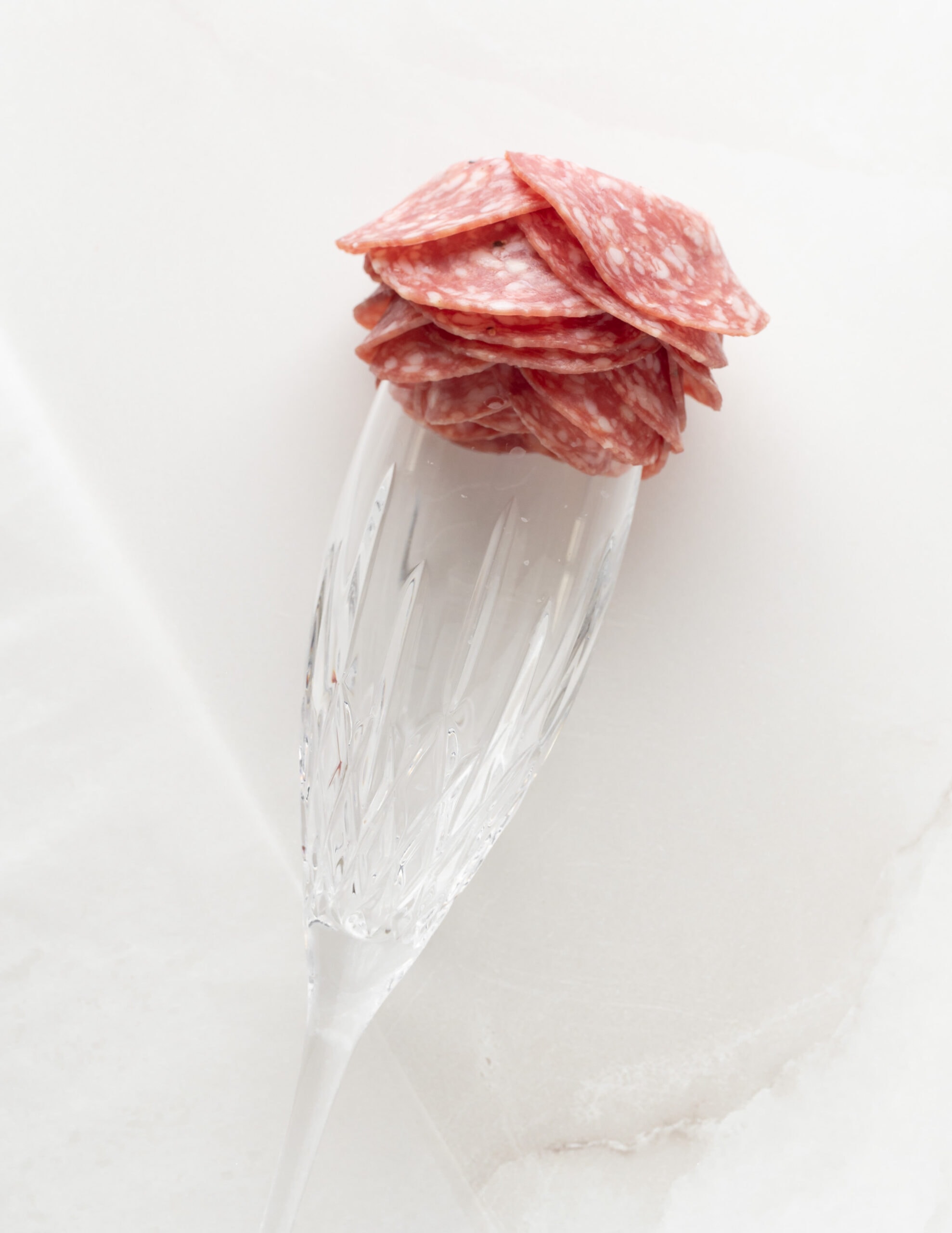 A champagne glass with 5 layers of salami, forming a salami rose. 