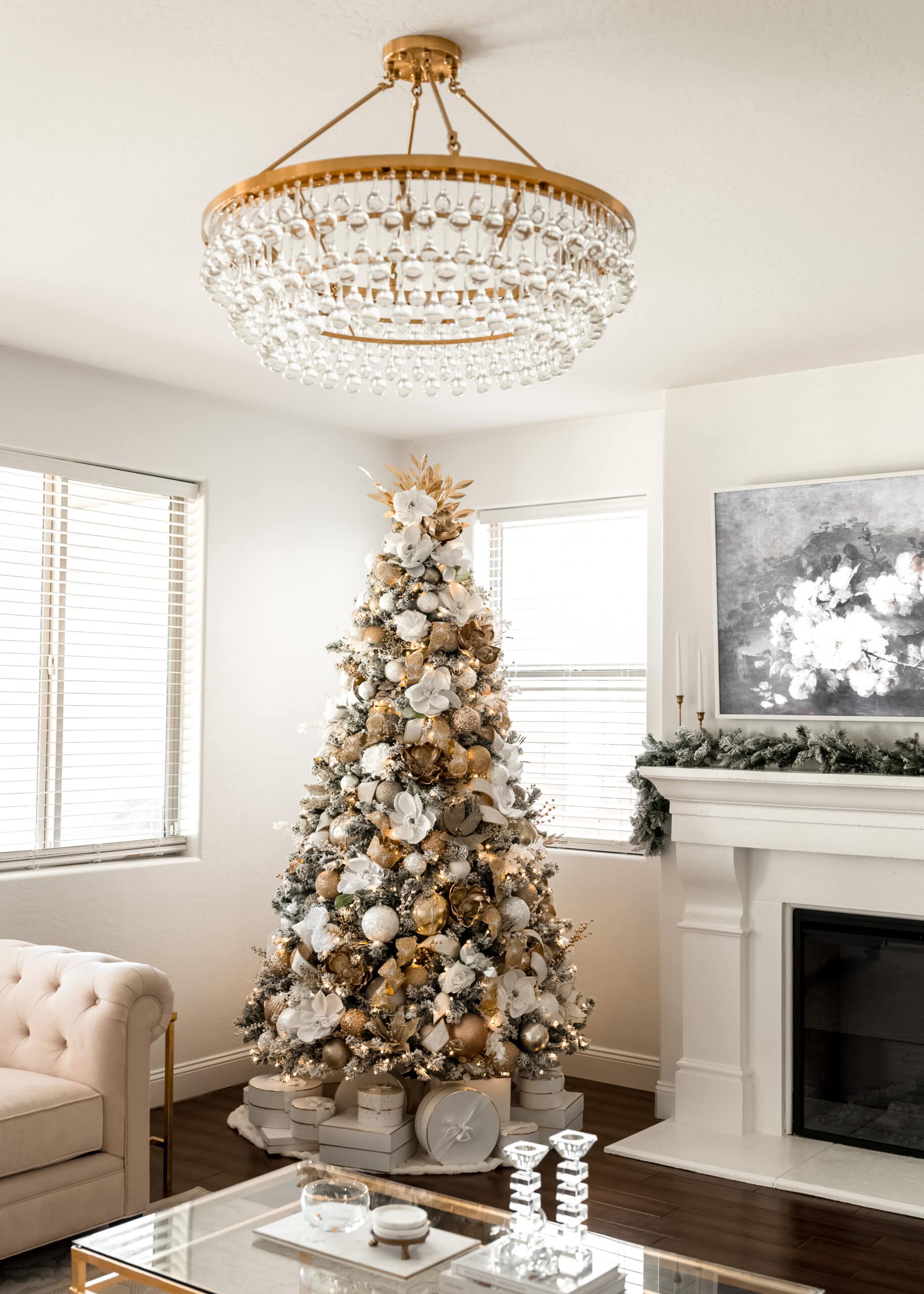 An 8 foot white and gold christmas tree with white and gold florals, white and gold ornaments, and white presents under the tree. 