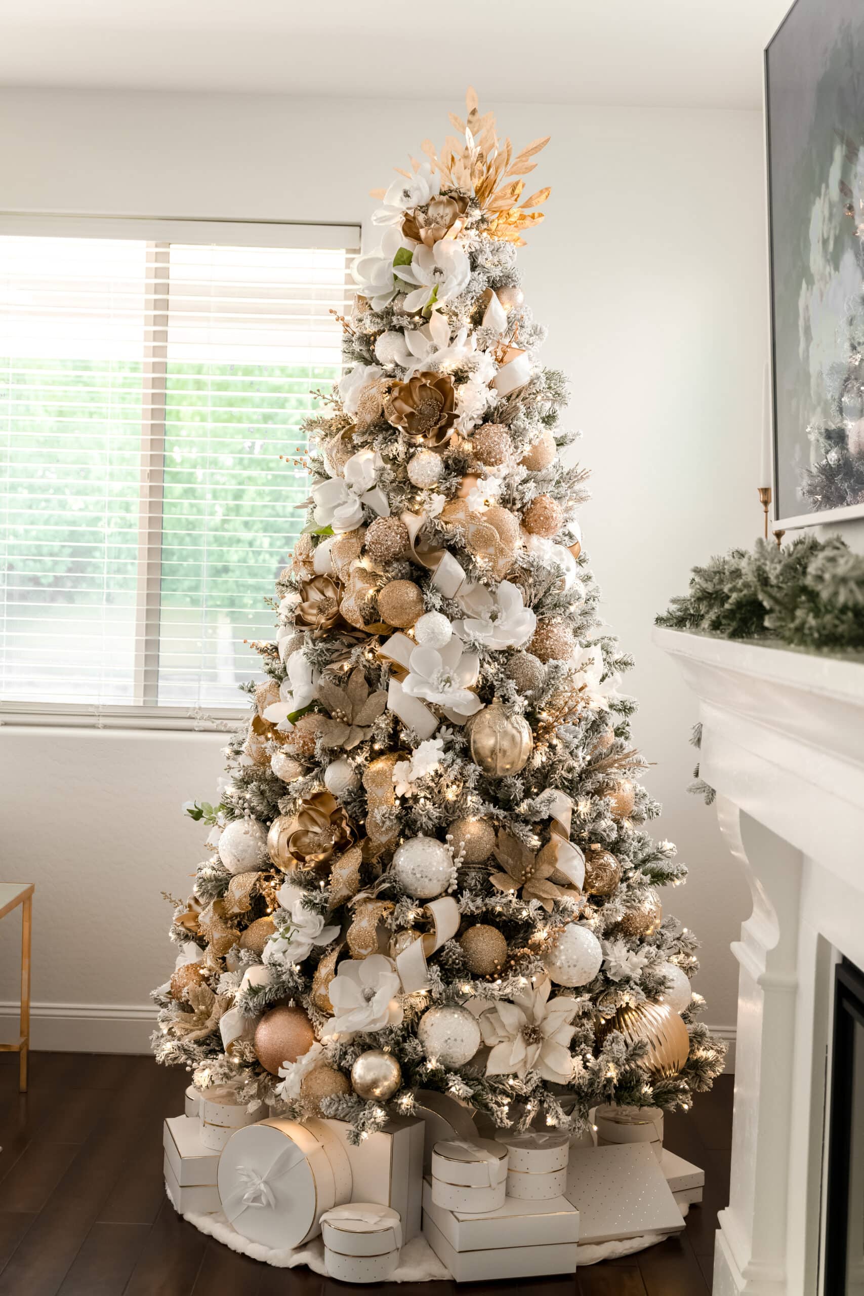 A side view of a white and gold christmas tree with white flowers, gold flowers, and a gold leaf tree topper. 