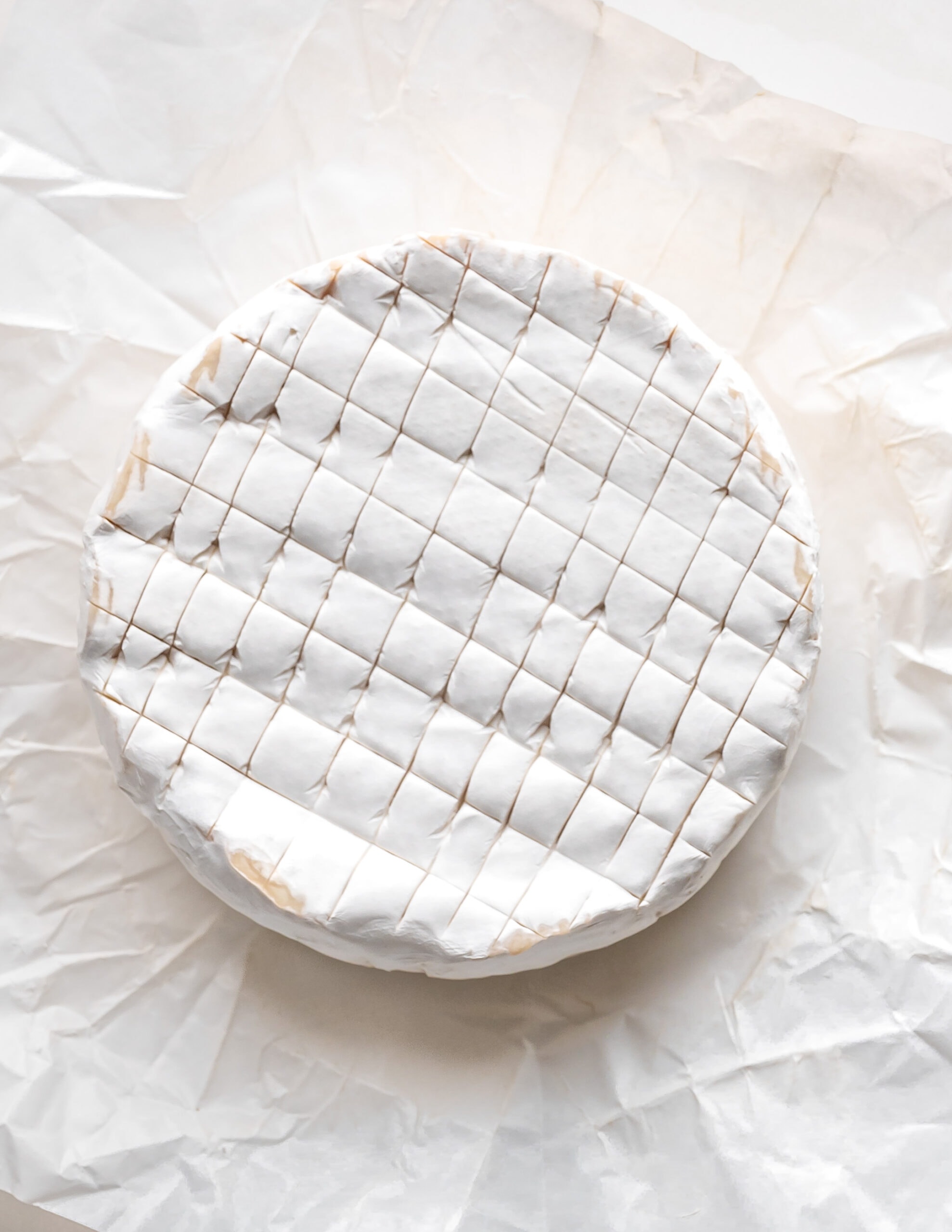 A picture of a round wheel of brie, with a crosshatch design. 