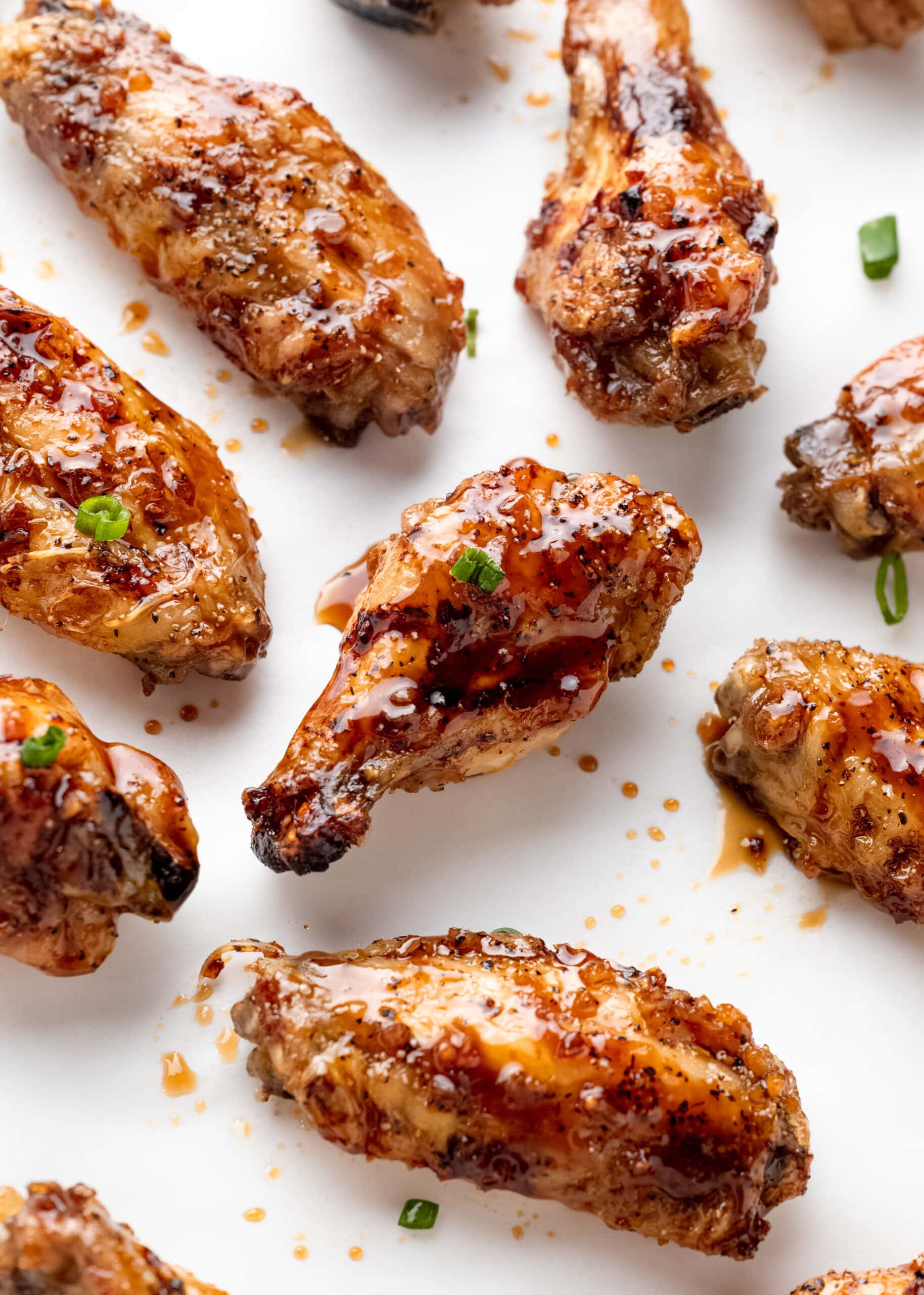 Honey garlic baked chicken wings with pieces of green onions.