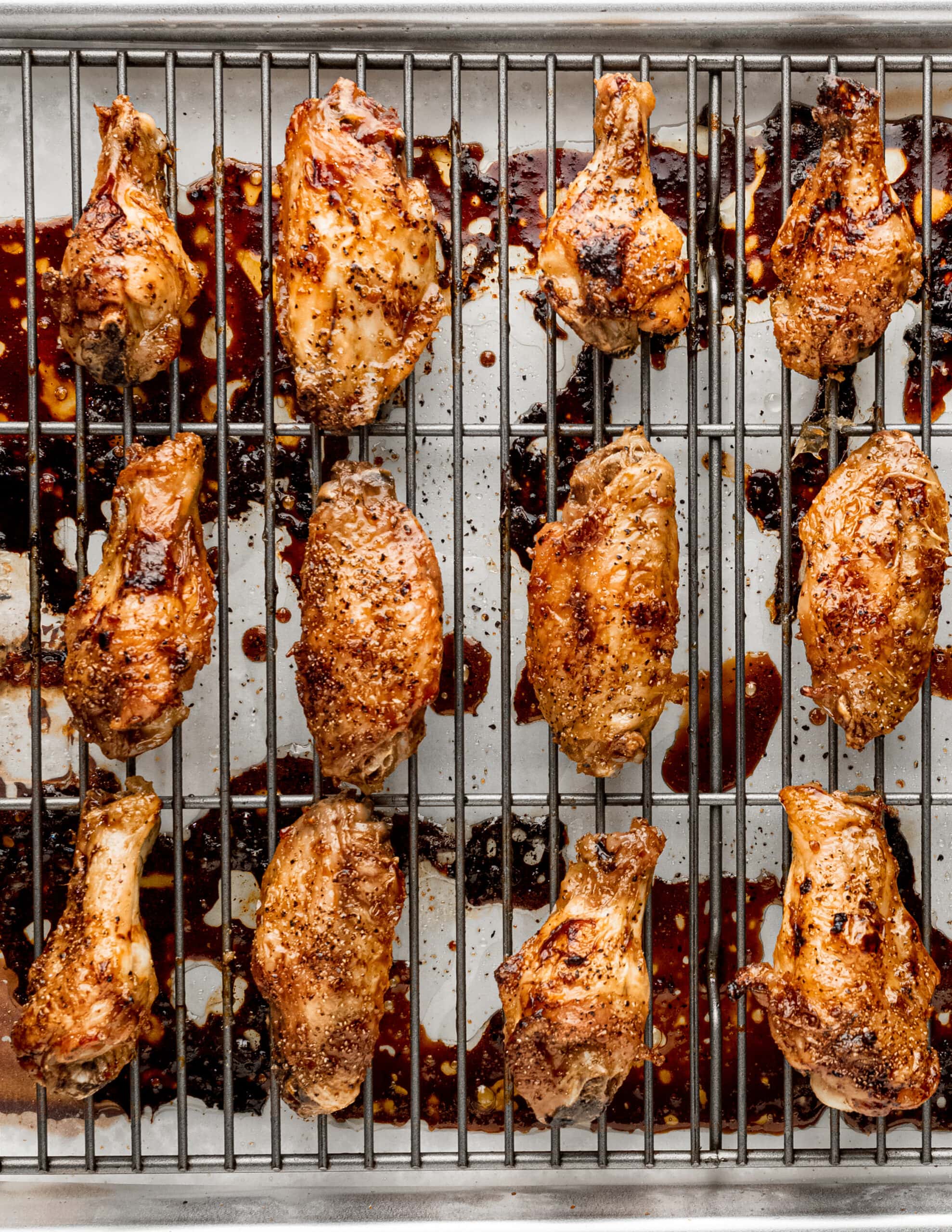 A metal baking rack with honey garlic ginger baked chicken wings glazed.