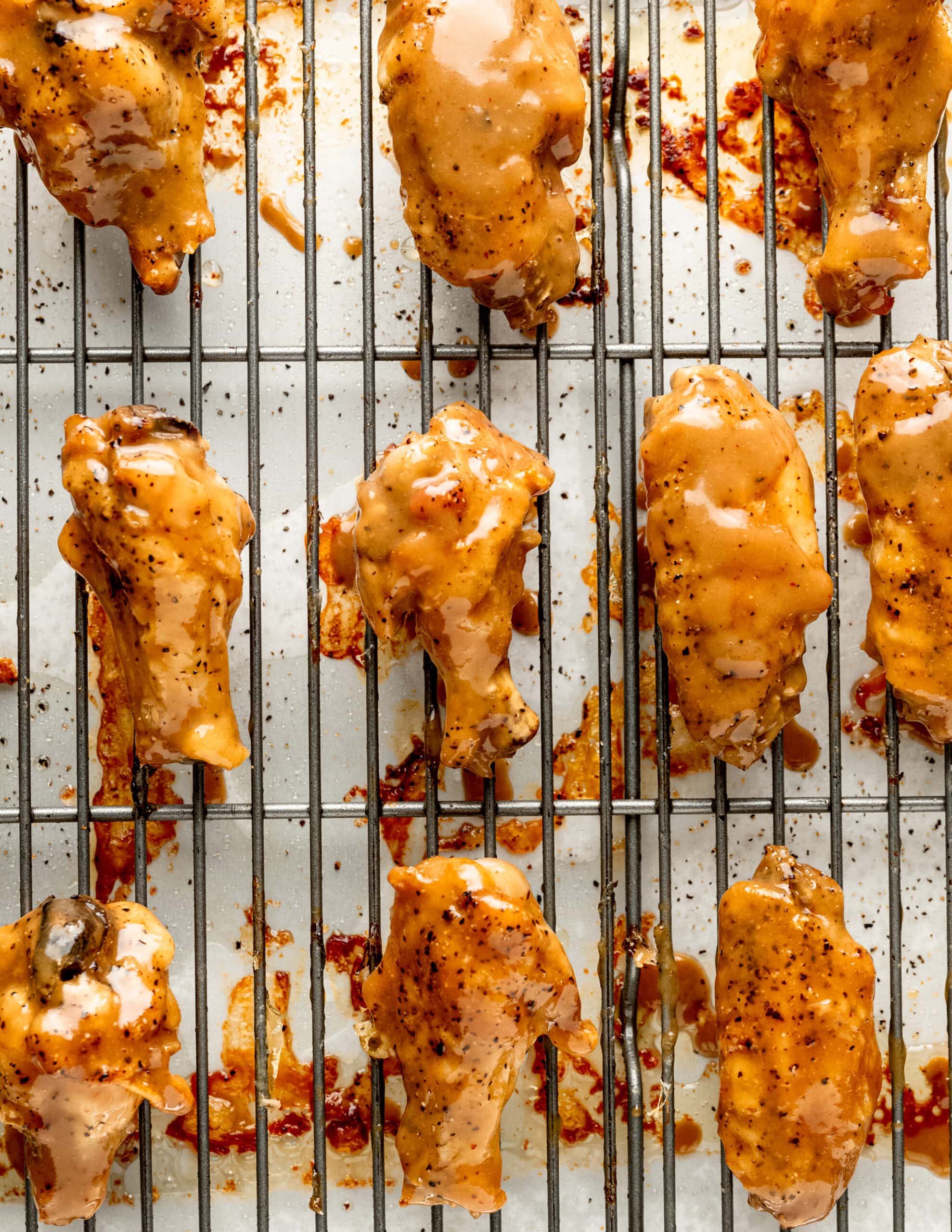 A lined rimmed baking sheet with honey mustard chicken wings, fully coated. 