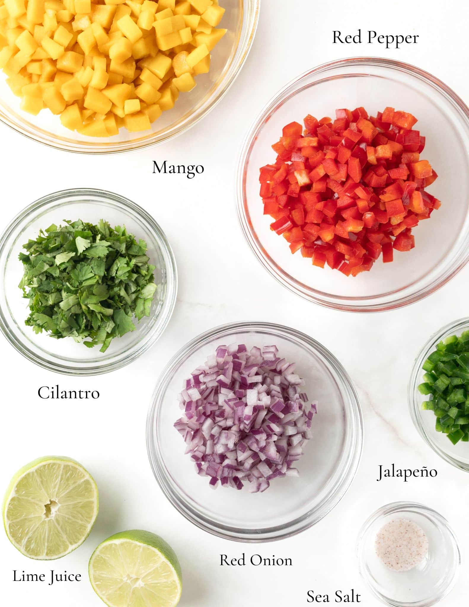 Ingredients for mango salsa in clear bowls.