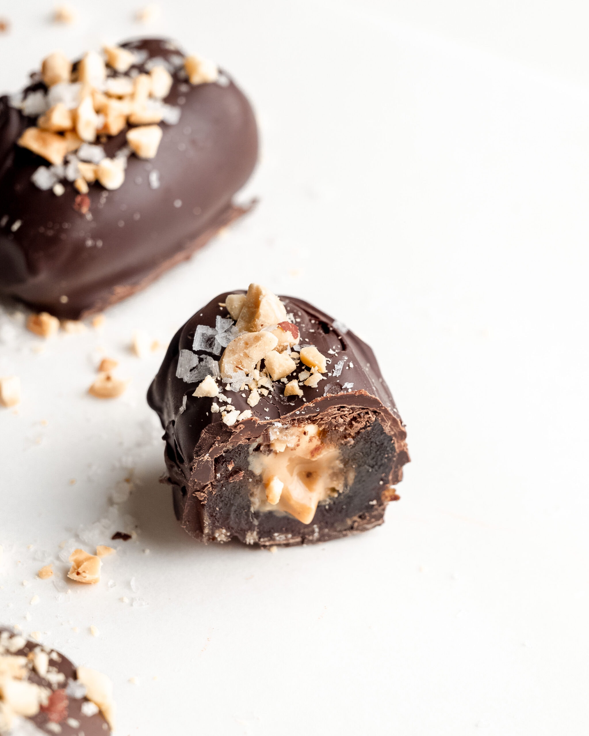 A chocolate covered stuffed date with peanut butter, cut in half with drippy peanut butter inside.