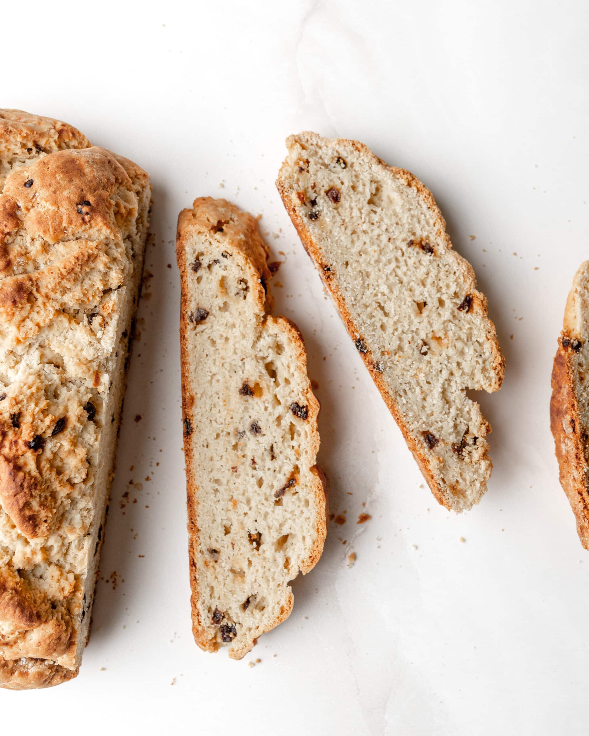 An overhead view of soda bread cut into three slices with currants.