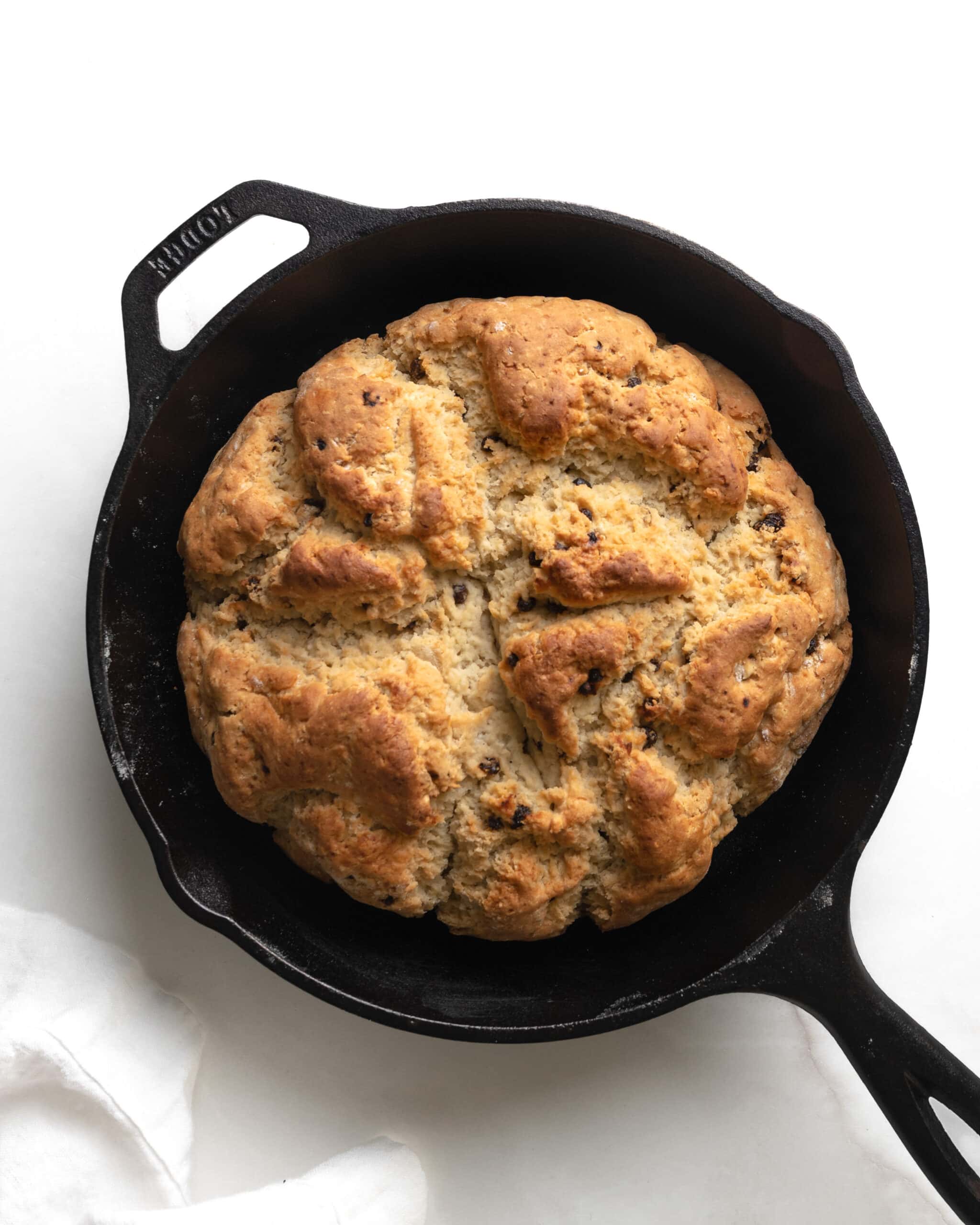 An overhead view of soda bread, baked in a cast iron skillet.