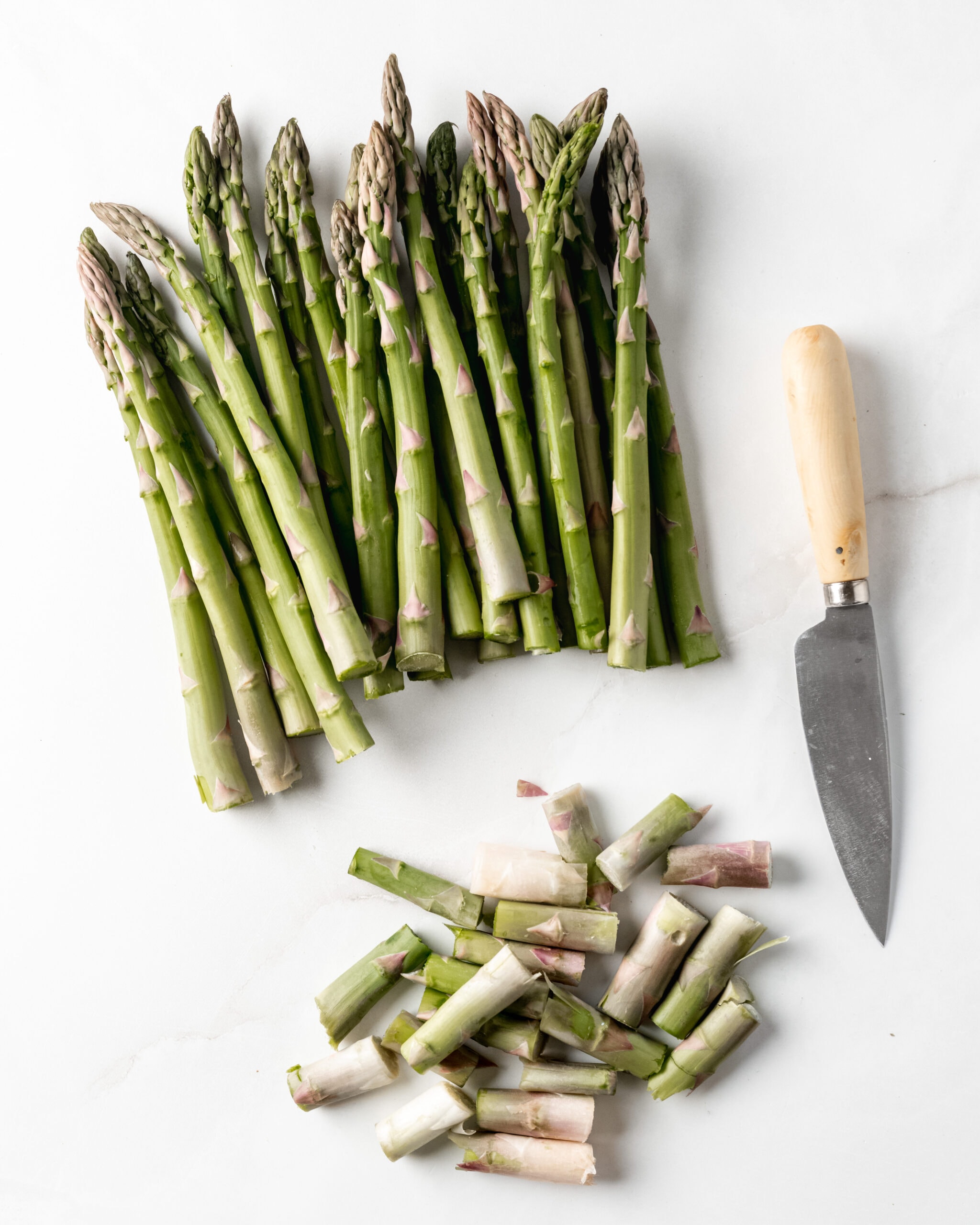 Asparagus with woody ends trimmed and a paring knife.
