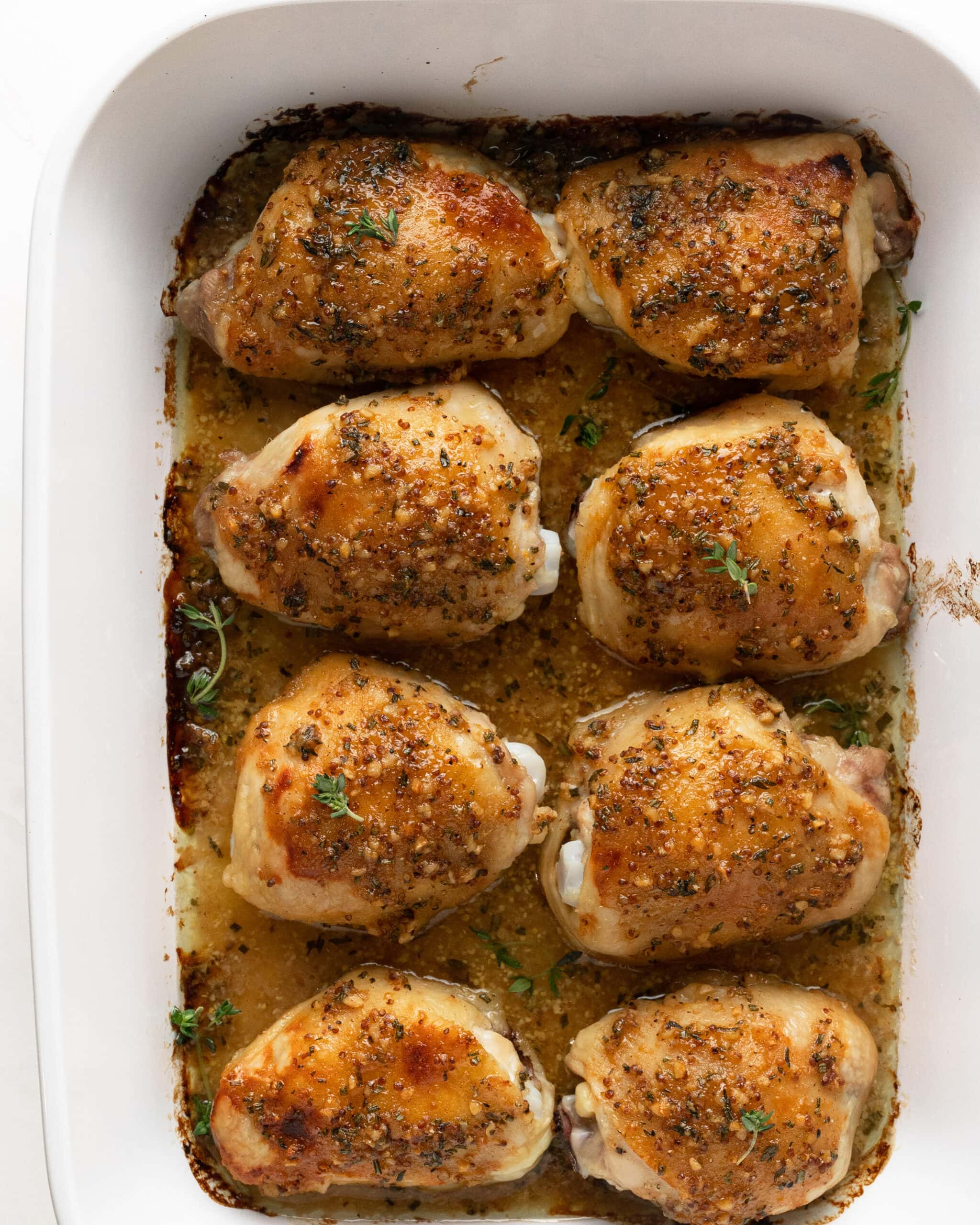 Large white rectangular pan with 8 bone-in chicken thighs topped with a honey mustard sauce.