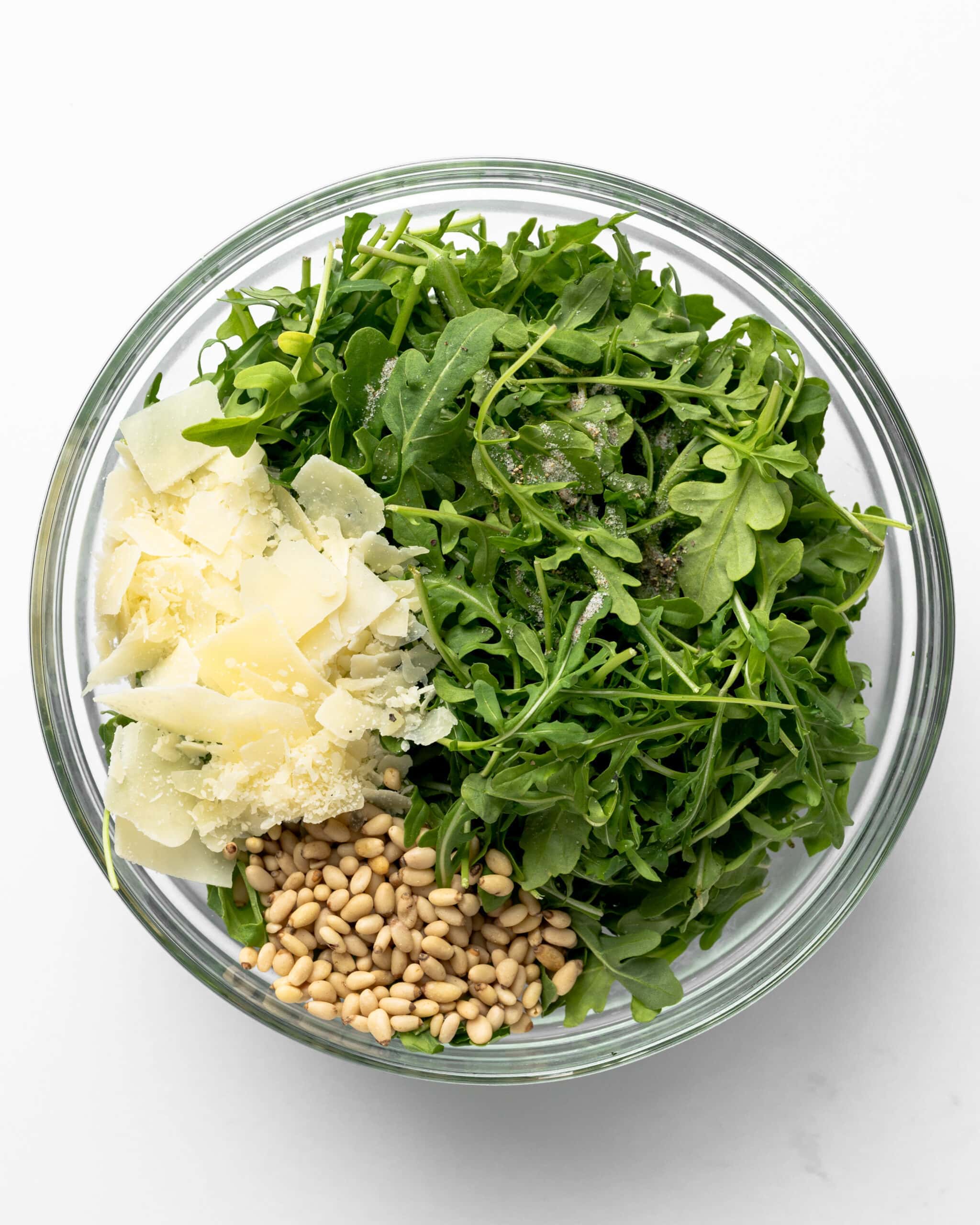 Rocket Salad in a bowl with parmesan and pine nuts.