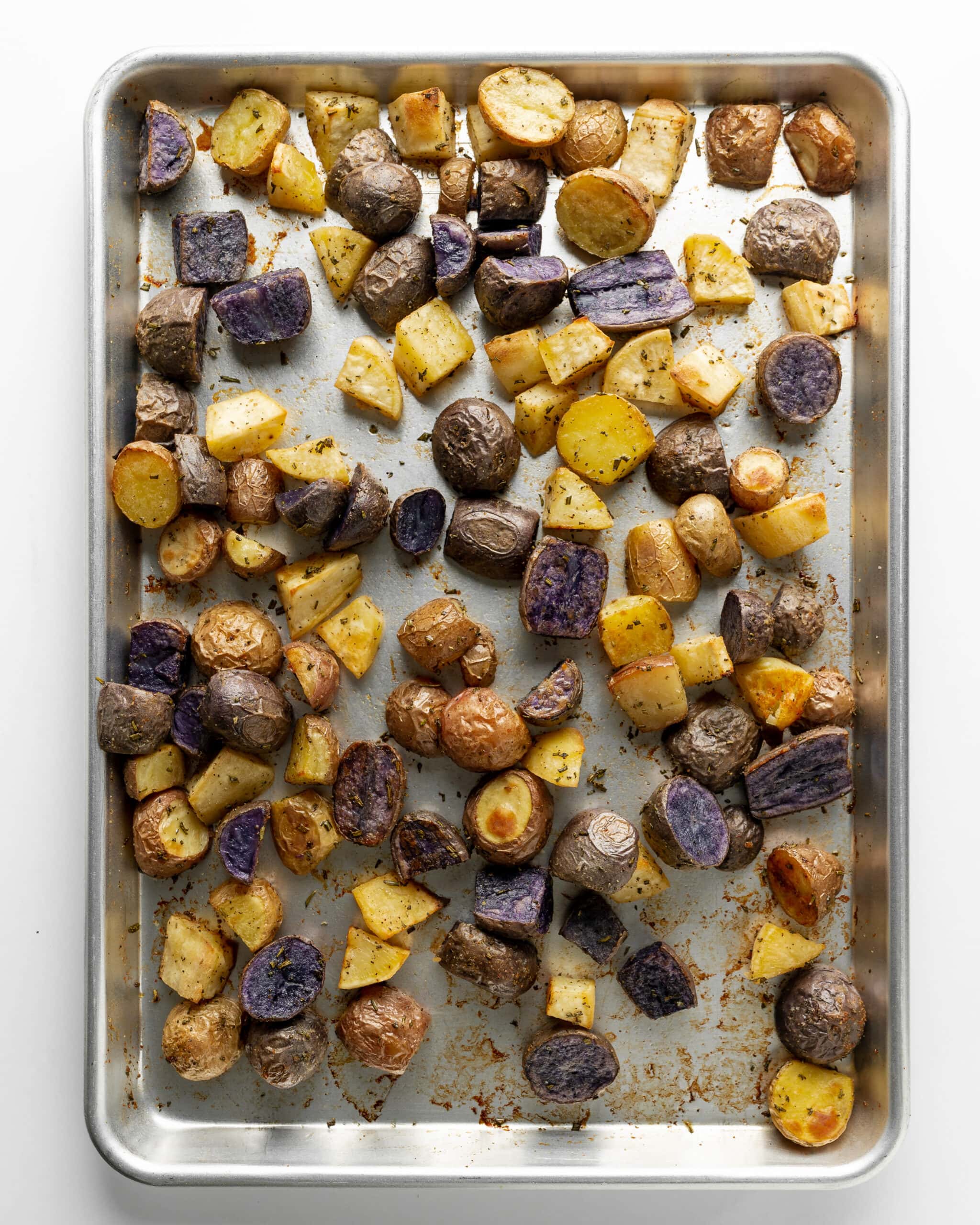 A large baking sheet with roasted rainbow potatoes out of the oven.